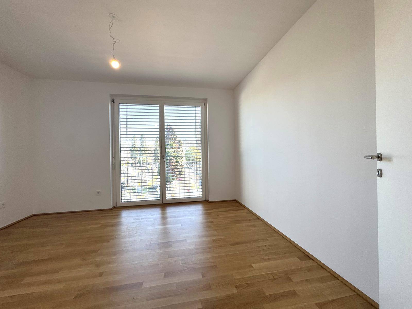 Geräumiges Zimmer mit Holzboden und Fenster, das sich ideal als Schlaf- oder Arbeitszimmer eignet.