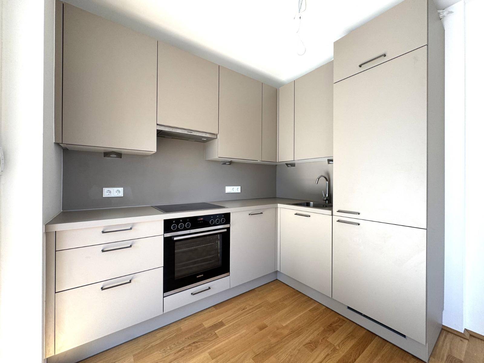 Neue, moderne Einbauküche mit grauen Schränken, Induktionskochfeld und integriertem Backofen.