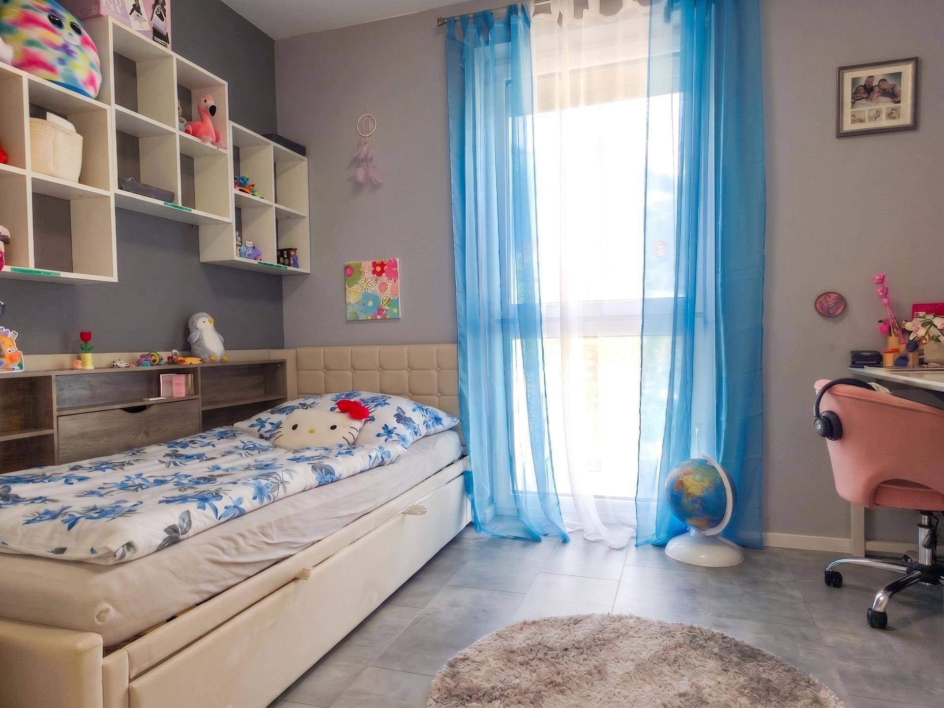 Kinderzimmer mit Bett, Schreibtisch und bunten Dekorationselementen.