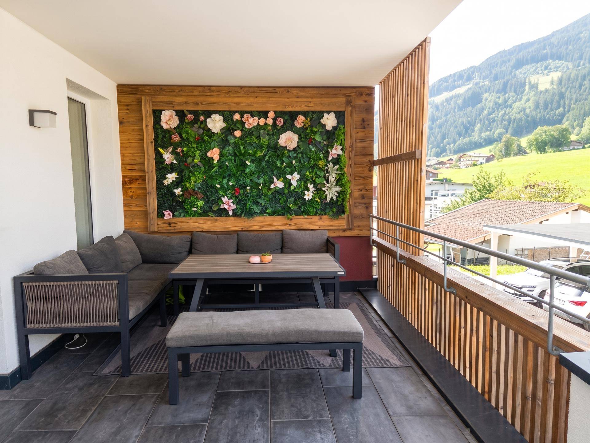 Gemütlicher Balkon mit Sitzgelegenheiten und Blick auf die grüne Berglandschaft.