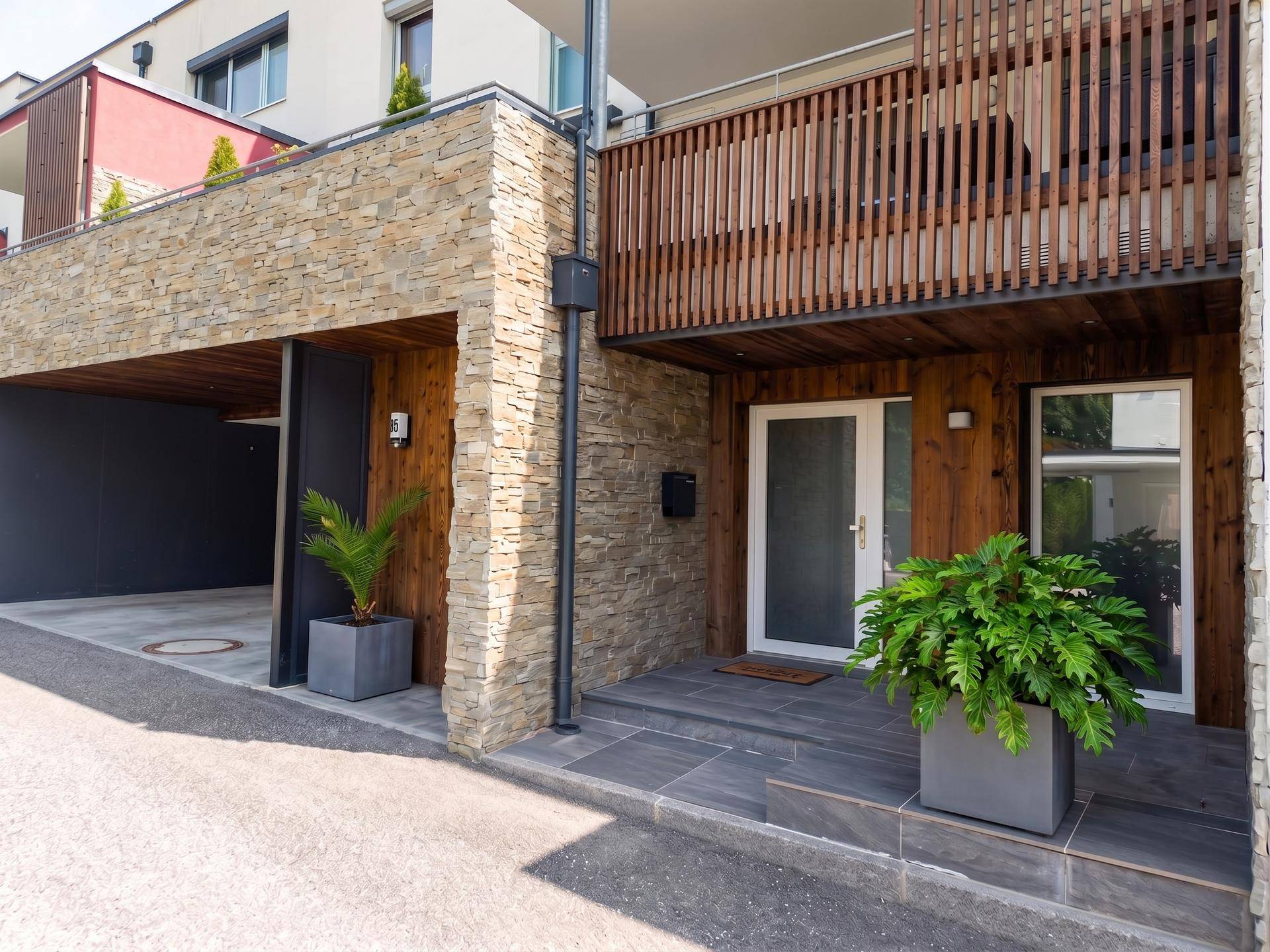 Eingangsbereich eines modernen Hauses mit Steinverkleidung und Holzdetails.
