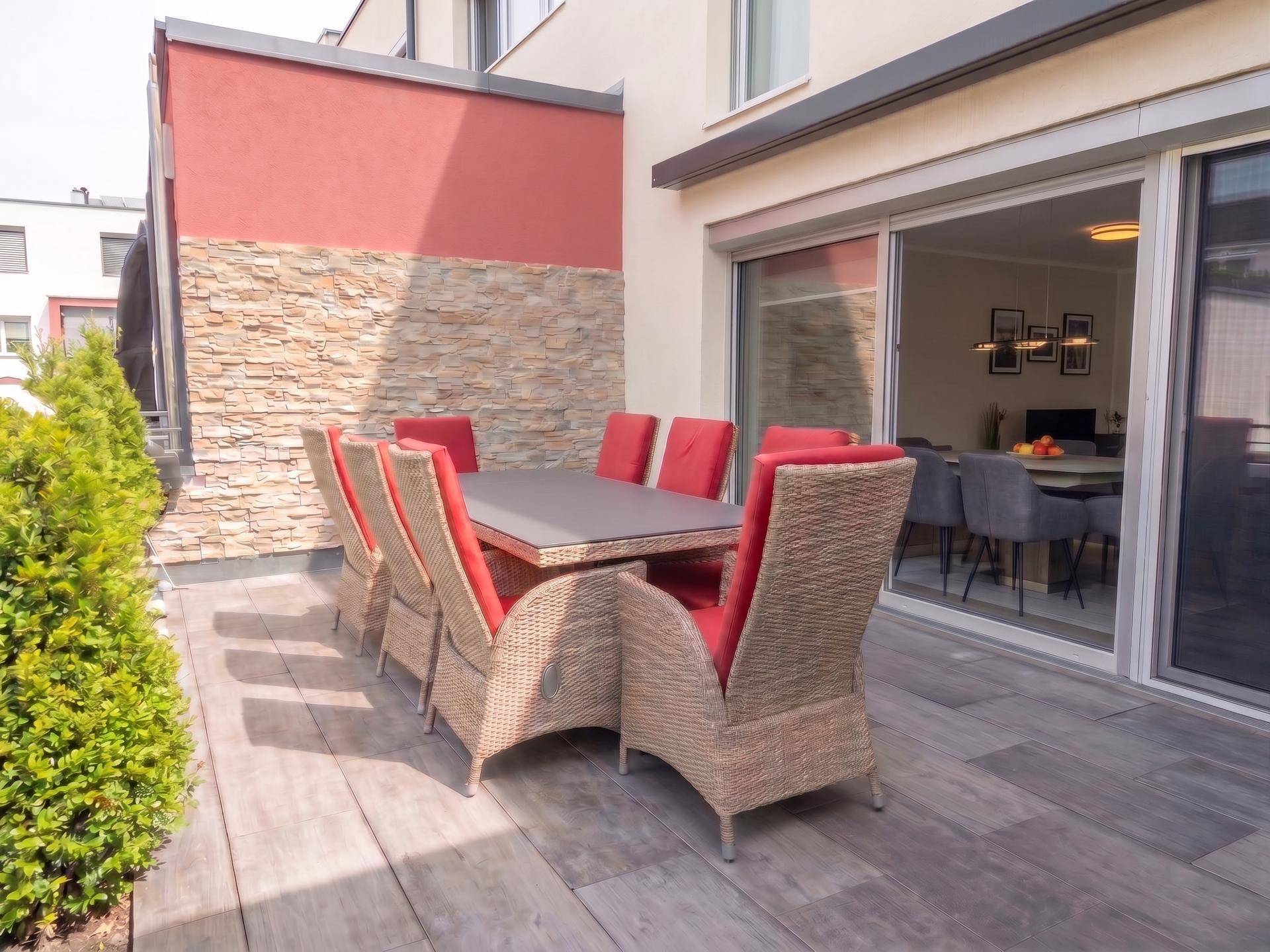 Geräumige Terrasse mit Esstisch und Stühlen, ideal für Mahlzeiten im Freien.