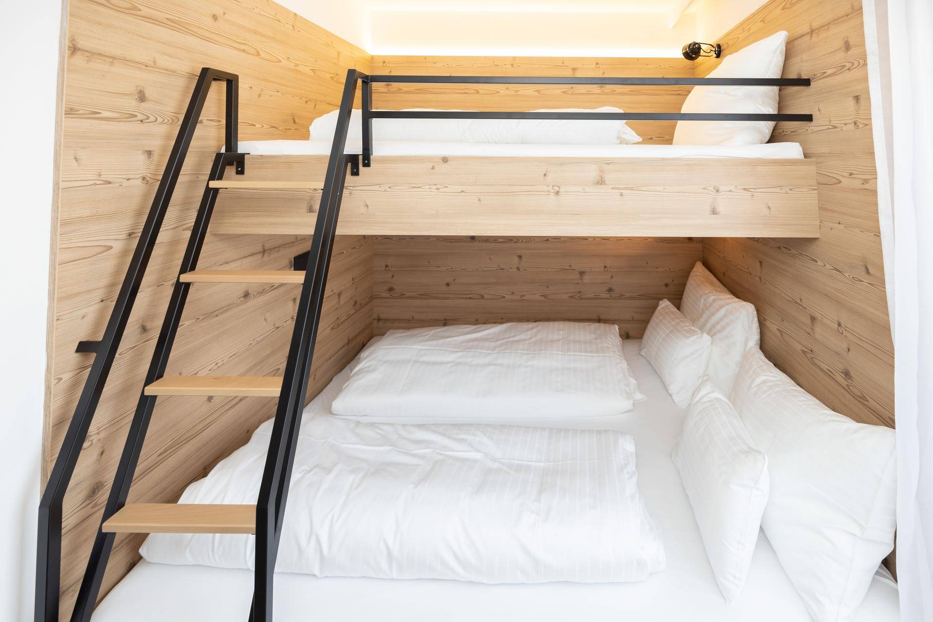Modernes Schlafzimmer mit Etagenbetten und Holzwänden, ideal für Kinder oder Gäste.