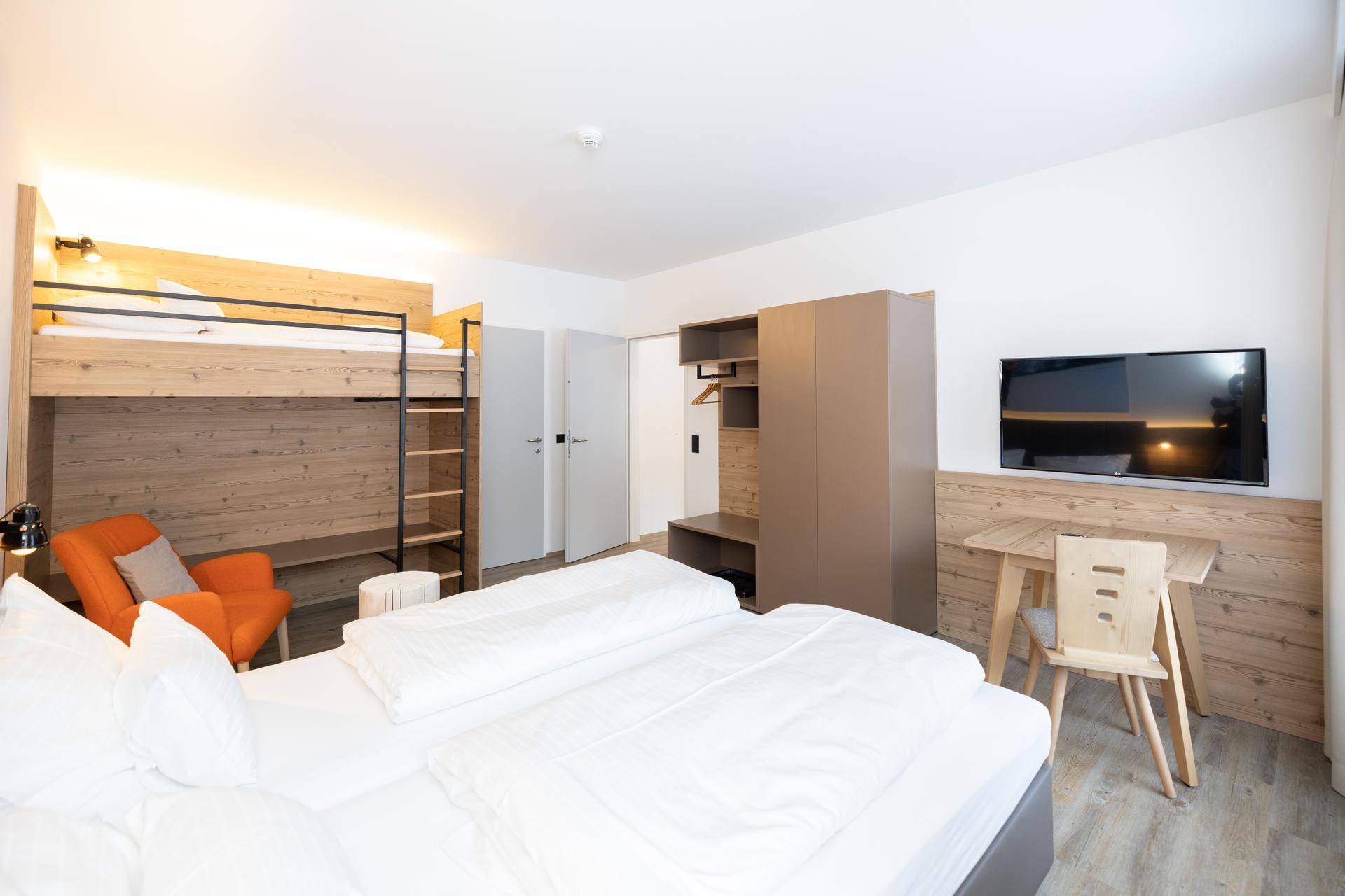 Geräumiges Schlafzimmer mit Doppelbett, Etagenbett, Schreibtisch und modernem Holzdekor.