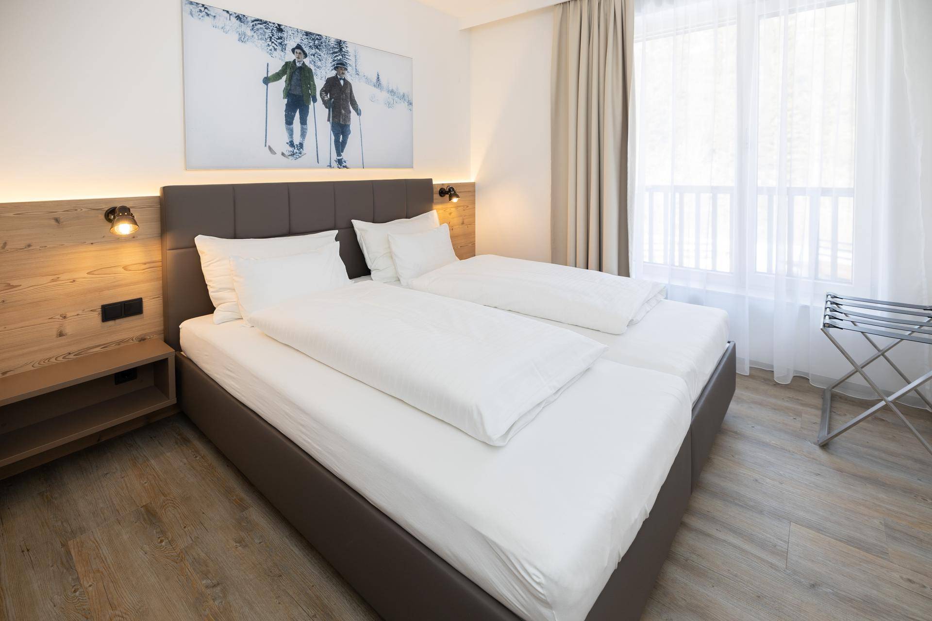 Komfortables Schlafzimmer mit Doppelbett, Holzelementen und Blick nach draußen.
