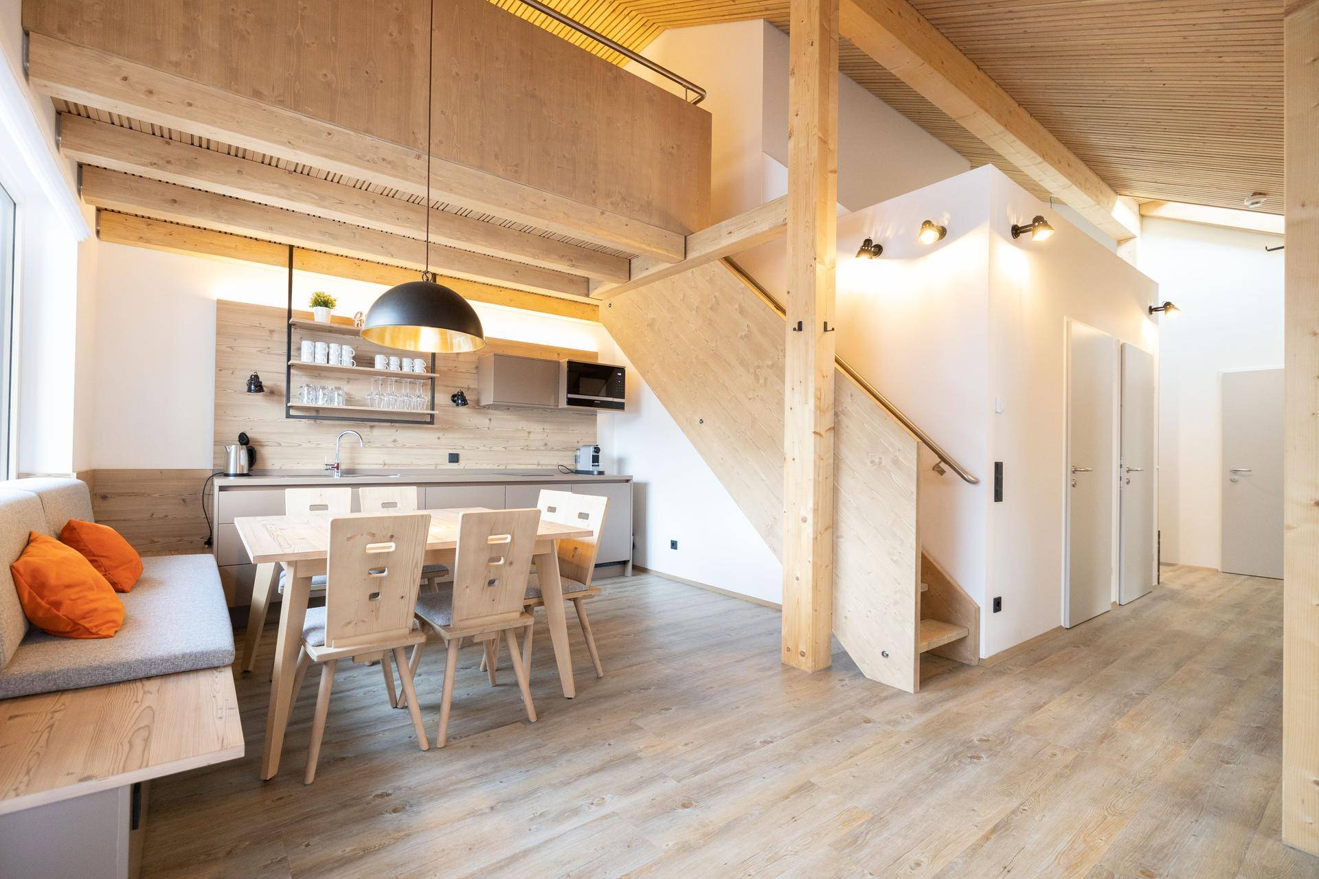 Offene Küche mit Essbereich, Holzbalken und Treppe zu einer oberen Ebene.