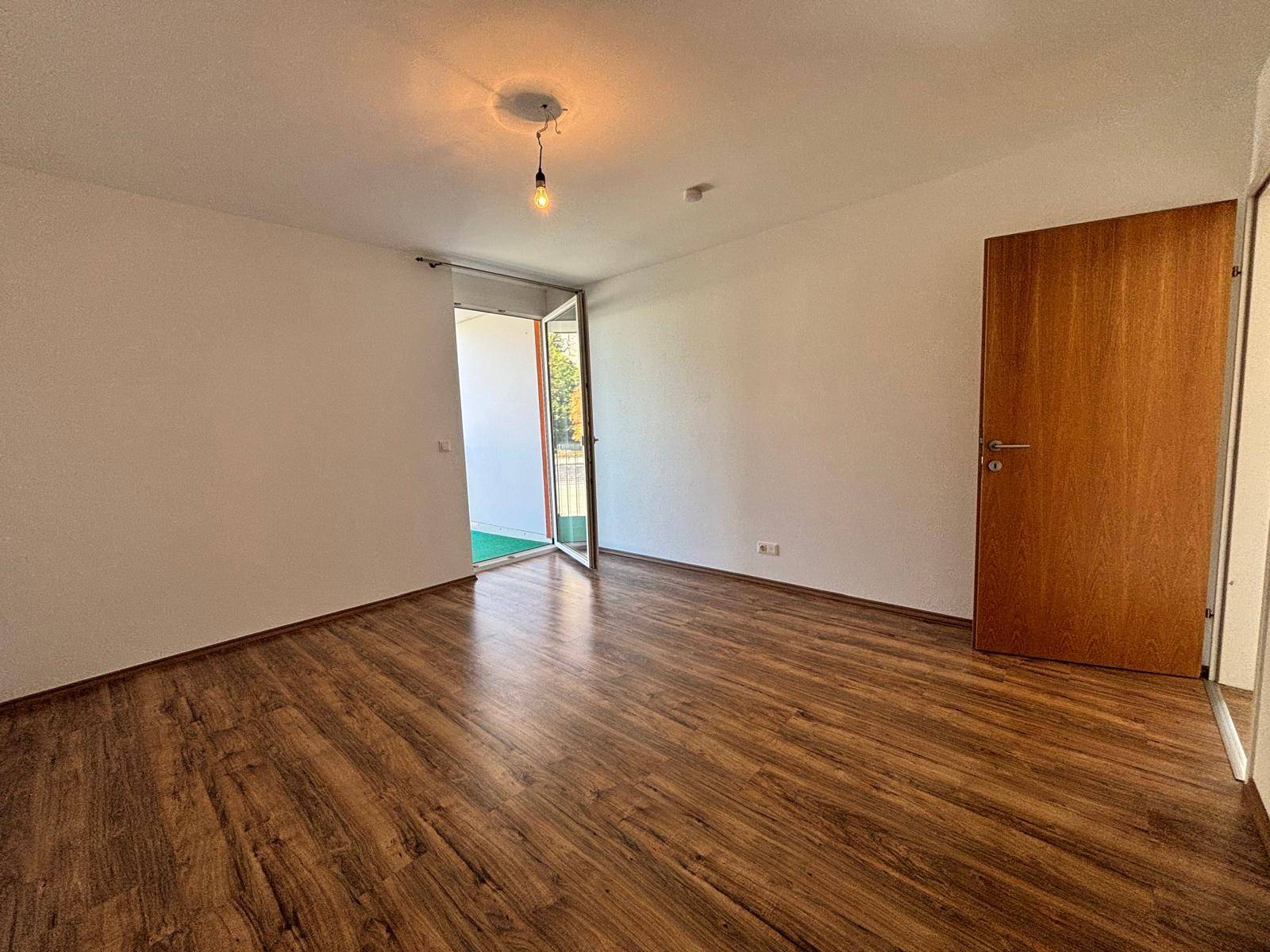 Helles Zimmer mit Laminatboden und direktem Zugang zu einem Außenbereich, ideal für frische Luft.