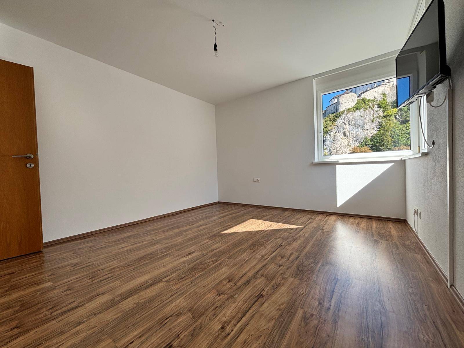 Helles Zimmer mit Laminatboden und einem Fenster, das einen direkten Blick auf die Festung bietet.