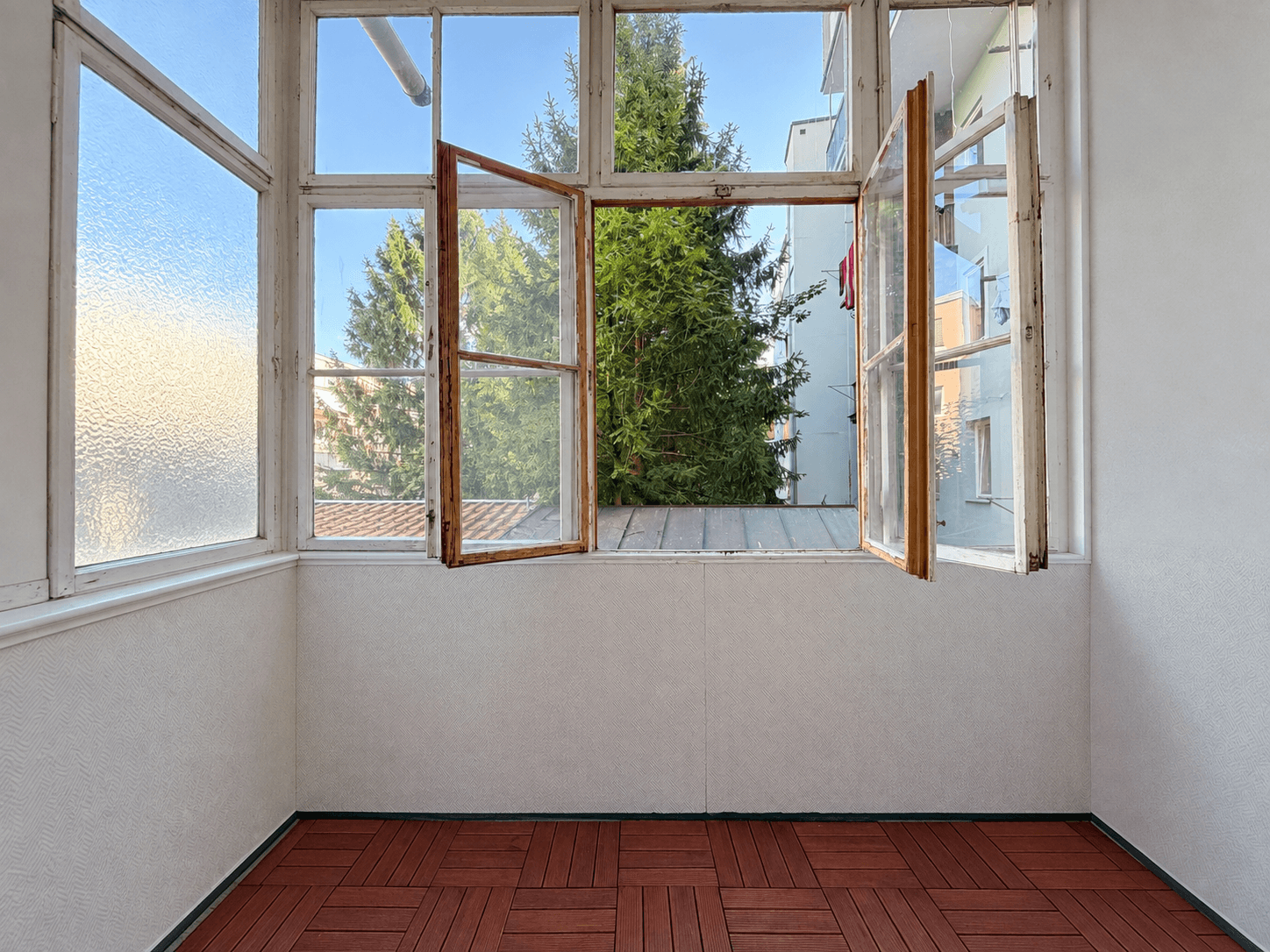 Heller Wintergarten mit vielen Fenstern und Blick ins Grüne, ideal zum Entspannen.