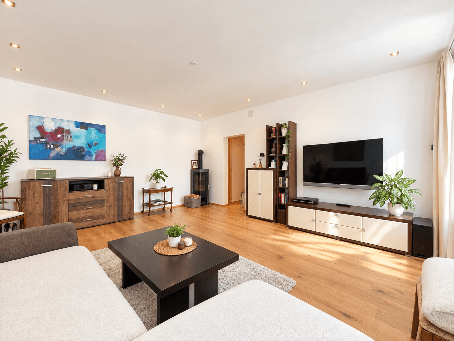 Helles Wohnzimmer mit bequemer Couch, Holzboden und einem stilvollen Kaminofen.