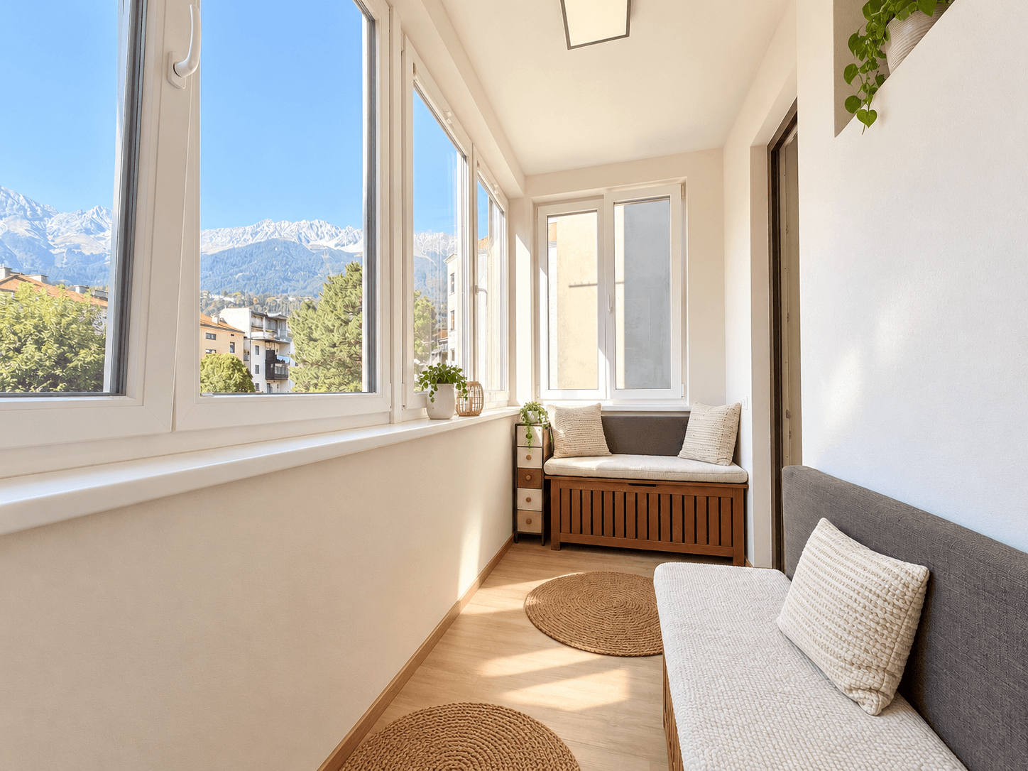 Helle Loggia mit Bergblick, Sitzbank und großen Fenstern für viel Tageslicht.