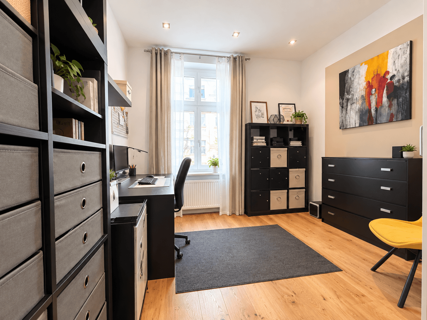 Helles Arbeitszimmer mit großem Fenster, Schreibtisch und farbenfrohem Kunstwerk.