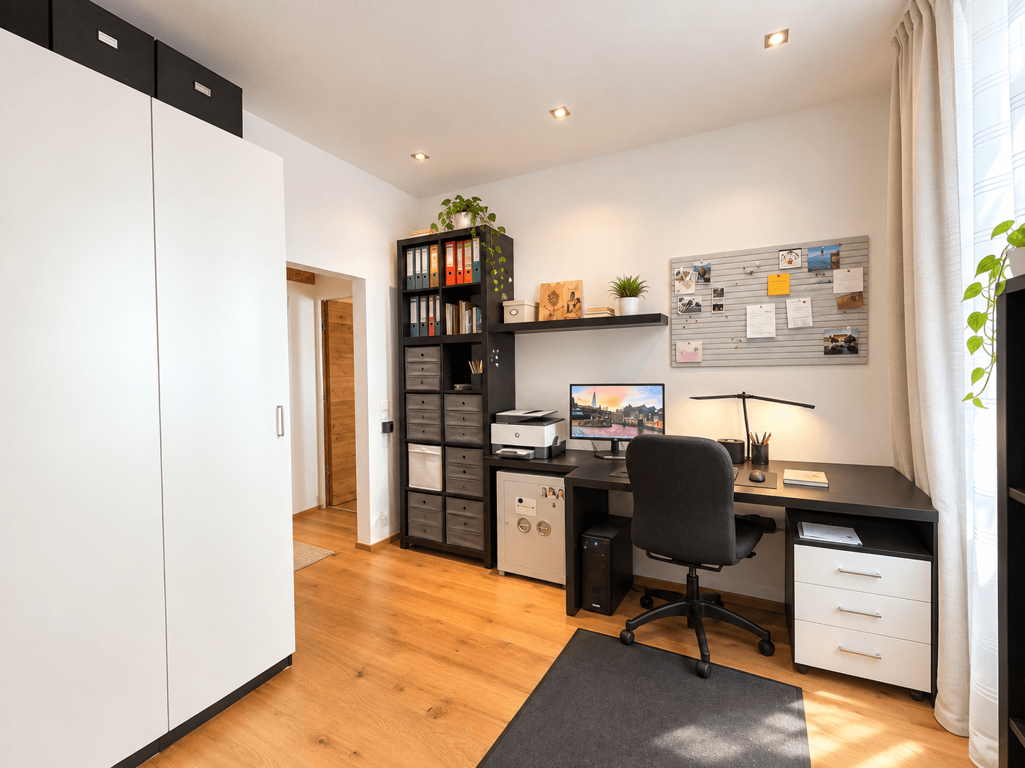 Modernes Arbeitszimmer mit Schreibtisch, Bürostuhl und viel Stauraum in Regalen.