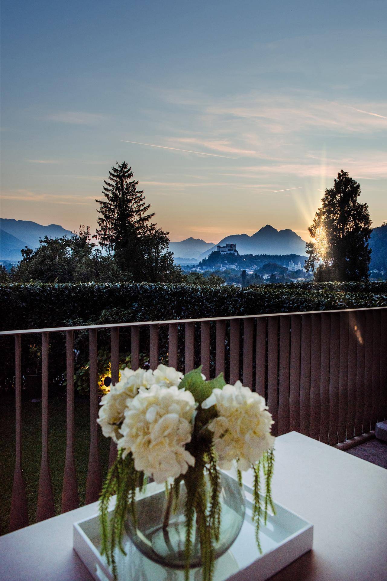 Blumenarrangement auf dem Balkon mit malerischem Blick auf die Berge und die Abenddämmerung.
