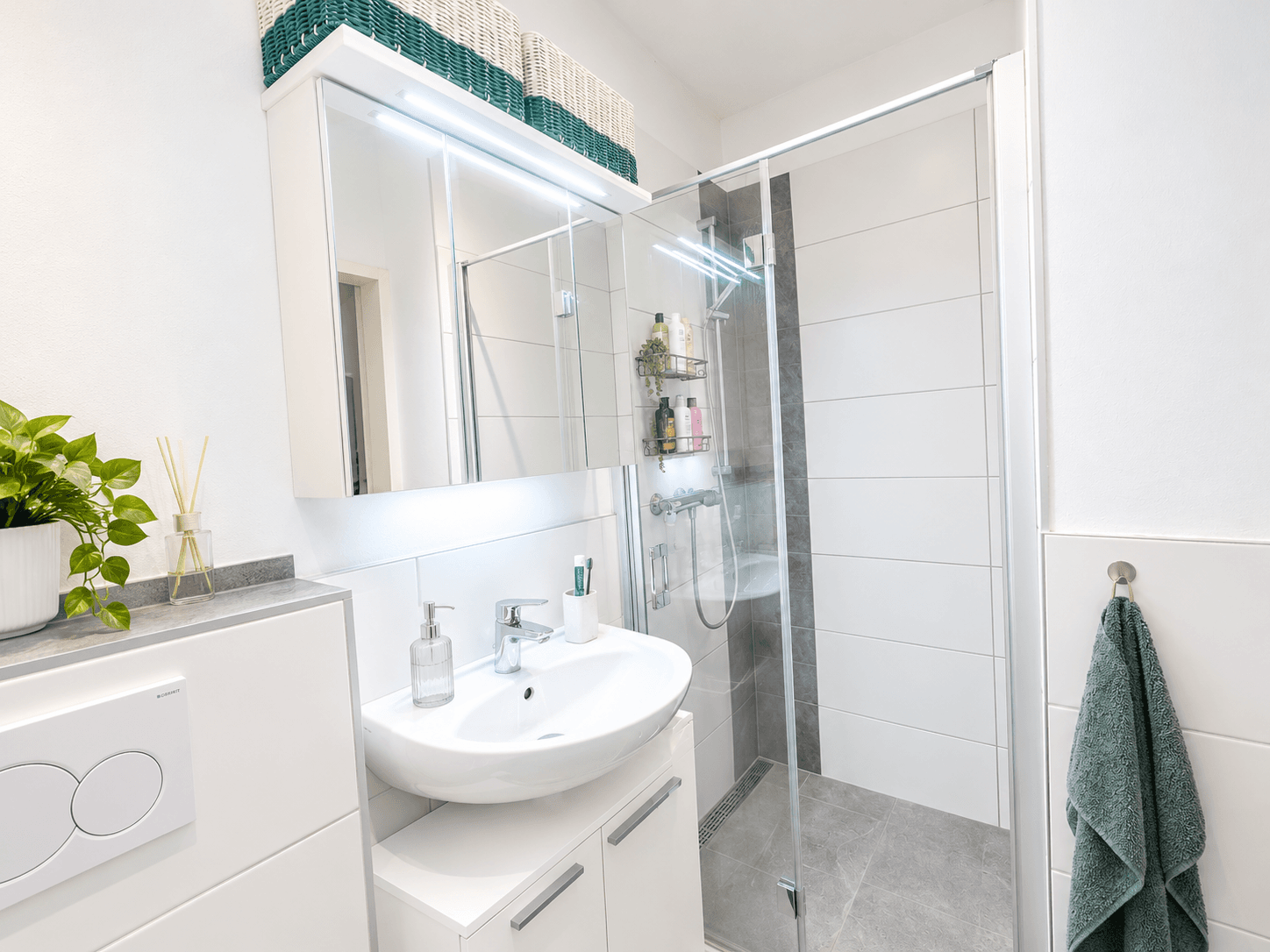 Helles Badezimmer mit moderner Duschkabine, Waschbecken und Spiegelschrank.