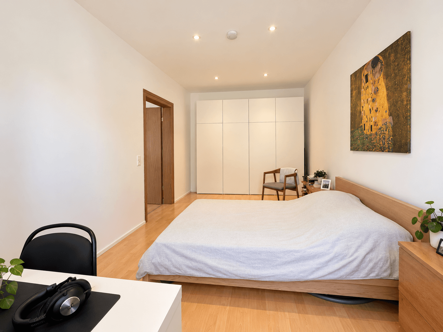 Gemütliches Schlafzimmer mit Holzbett, Einbauschränken und einem Kunstwerk an der Wand.