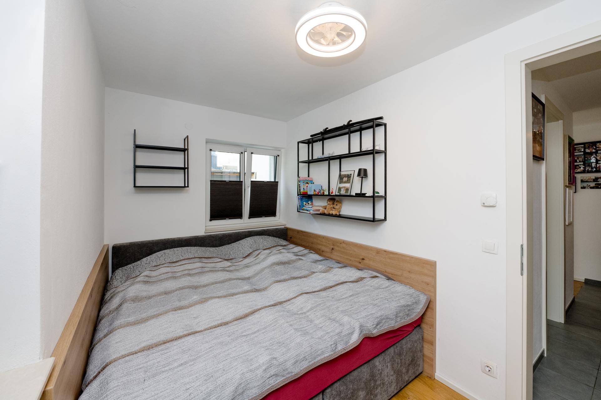 Gemütliches Schlafzimmer mit Einzelbett, Holzboden und Wandregalen.
