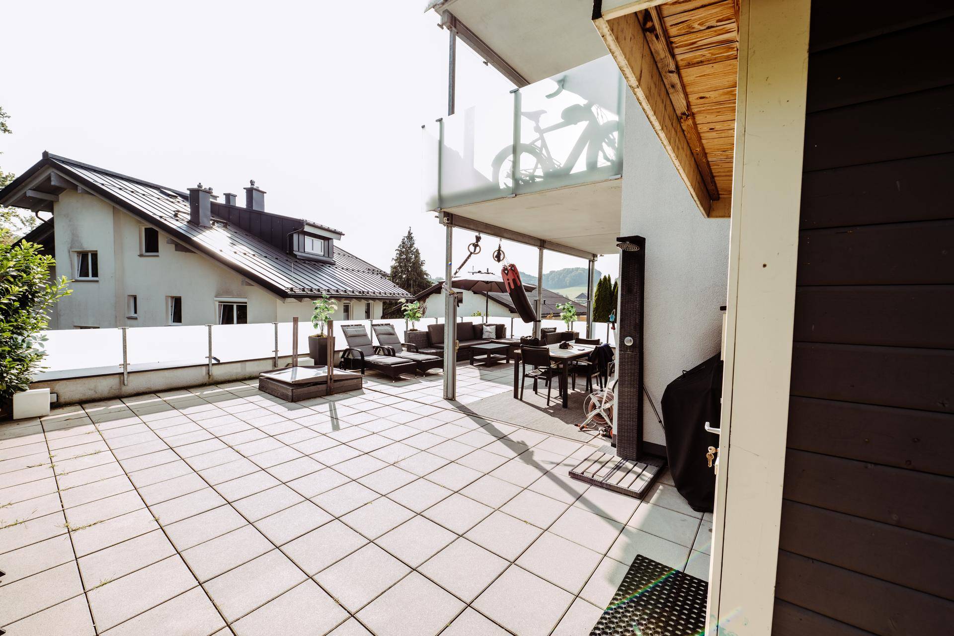 Weitläufige Terrasse mit verschiedenen Sitzbereichen und Blick auf das Wohngebäude.