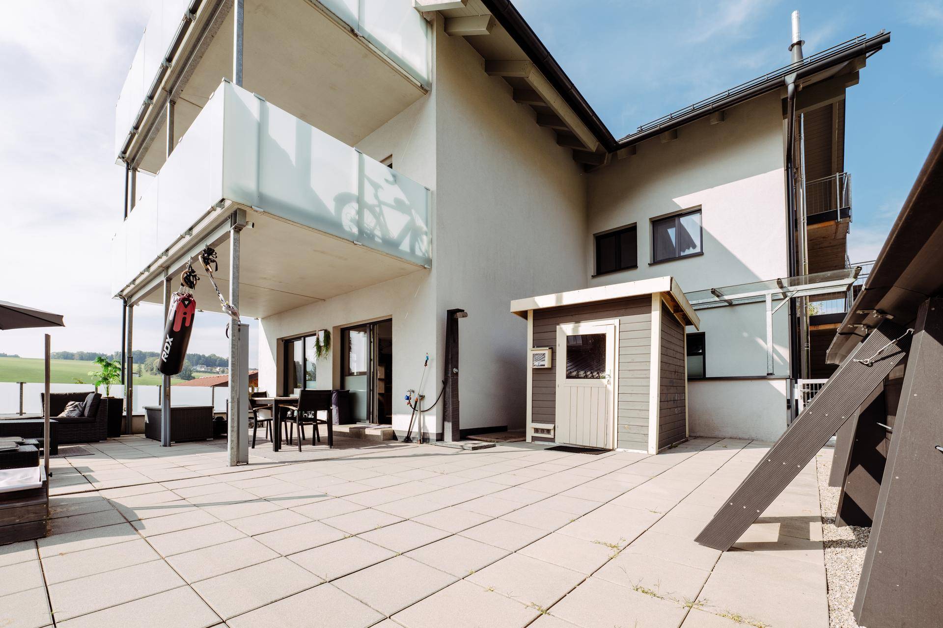 Weitläufige Terrasse mit Außensauna, Sitzbereich und Blick auf die Landschaft.