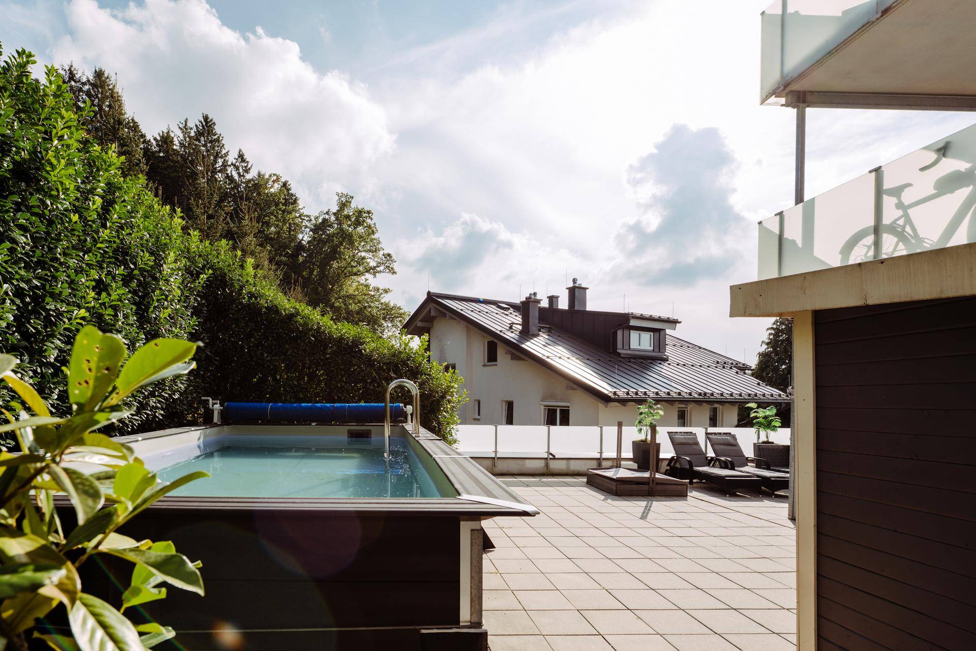 Große Terrasse mit kleinem Pool, Liegestühlen und Blick auf die umliegende Natur.