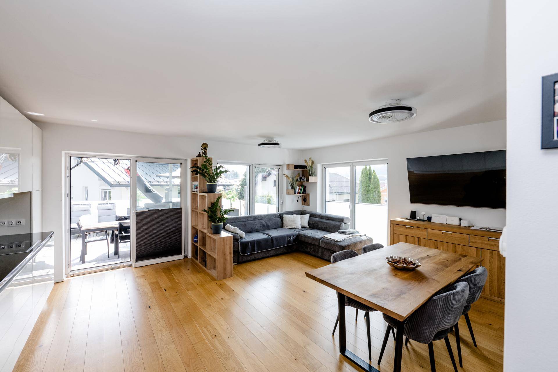 Geräumiger Wohn-Essbereich mit Ecksofa, Holzboden und großen Fenstern zur Terrasse.