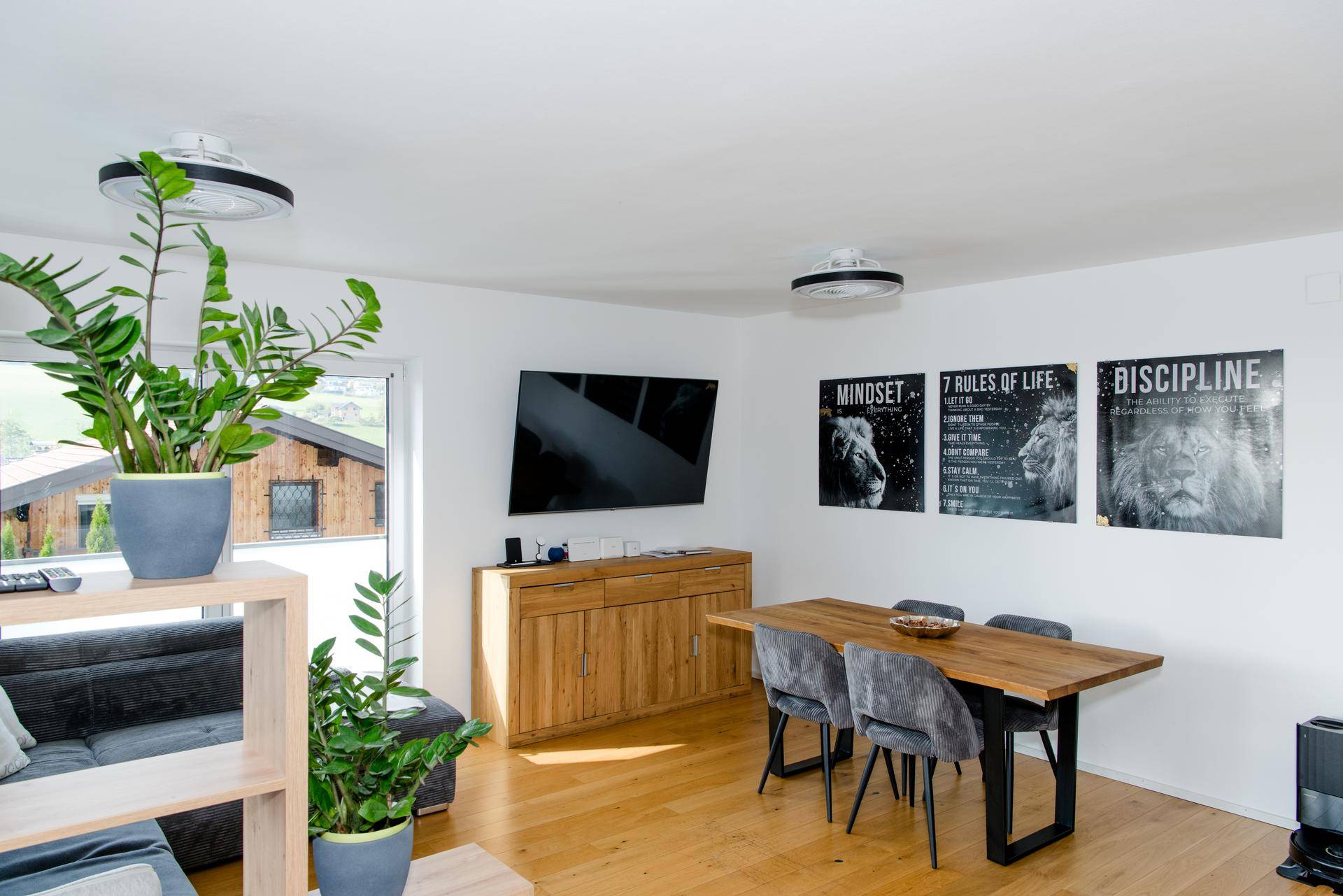 Heller Wohnbereich mit Holzboden, Esstisch, Sofa und Blick auf die umliegende Landschaft.