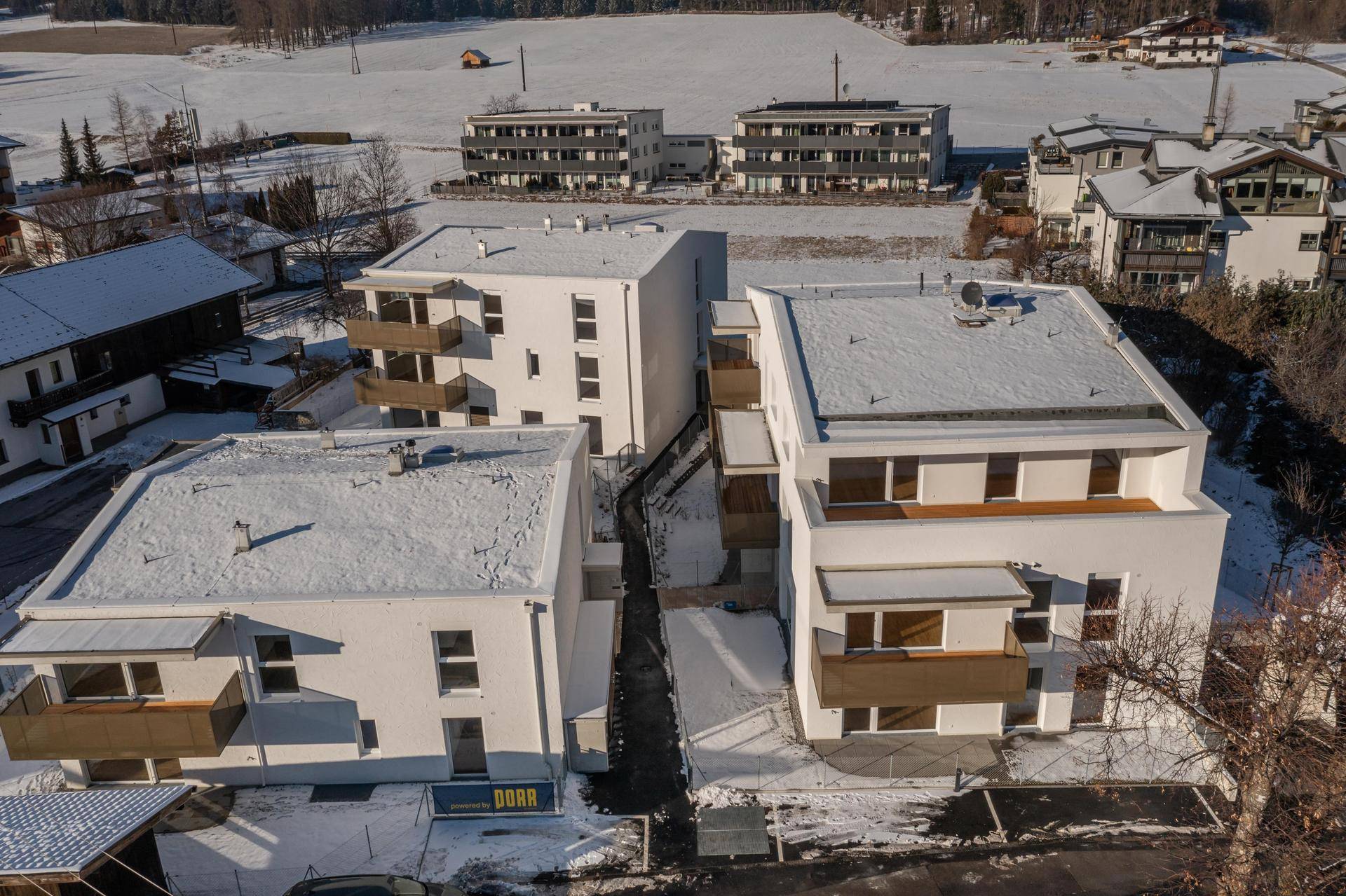 Luftaufnahme von modernen Wohngebäuden in einer schneebedeckten Landschaft.