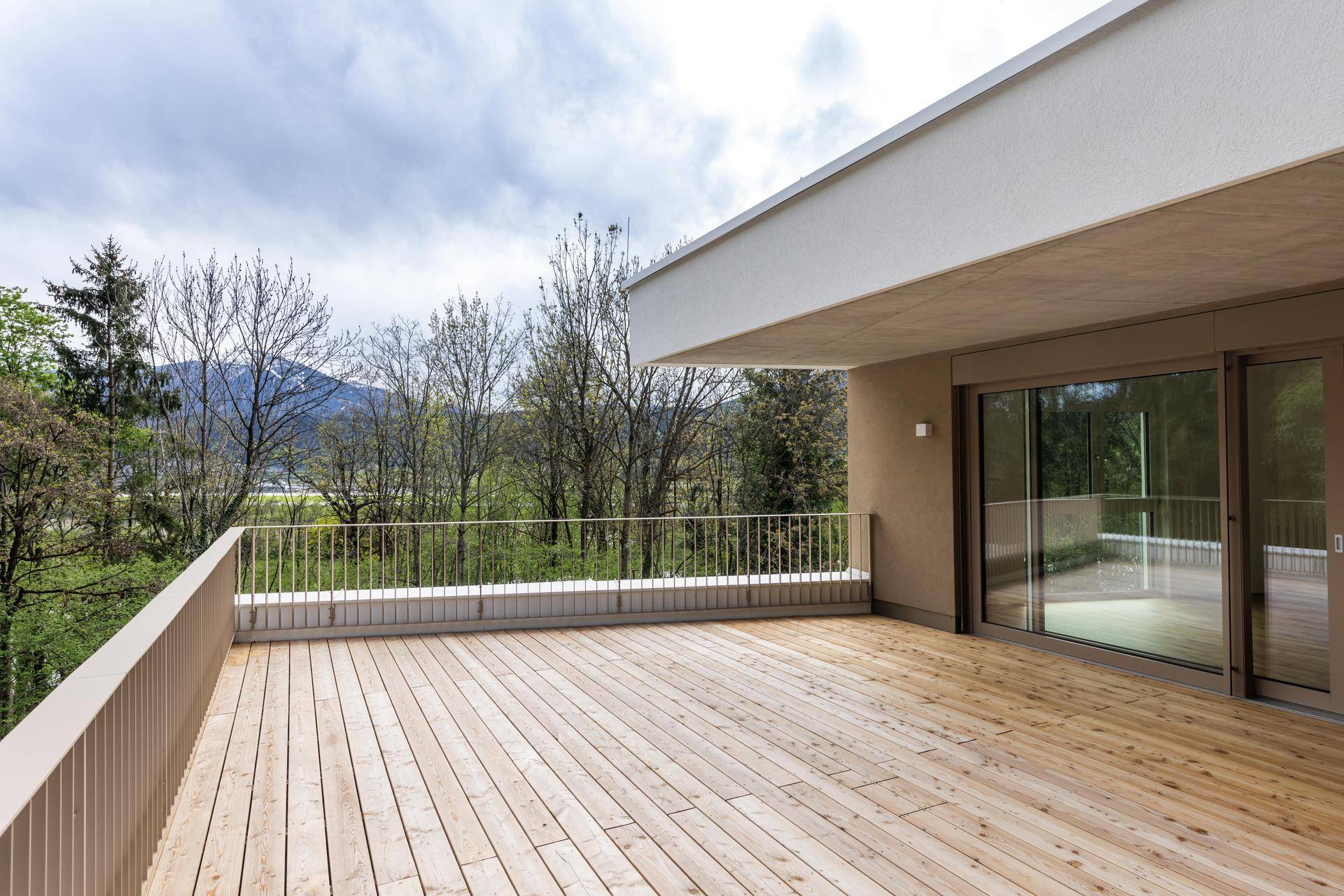 Große Holzterrasse mit moderner Fassade und weitem Blick auf die Landschaft.