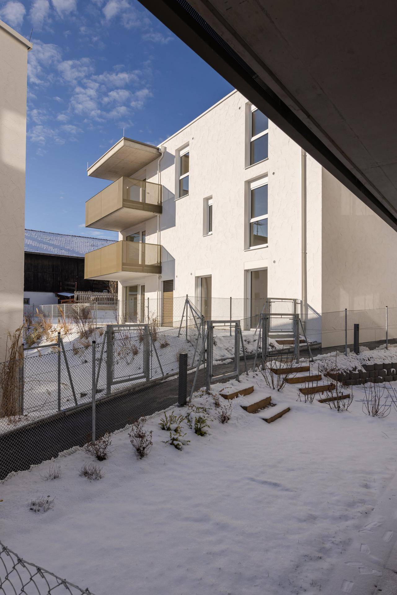 Neubaugebäude mit modernen Balkonen und schneebedecktem Gartenbereich.