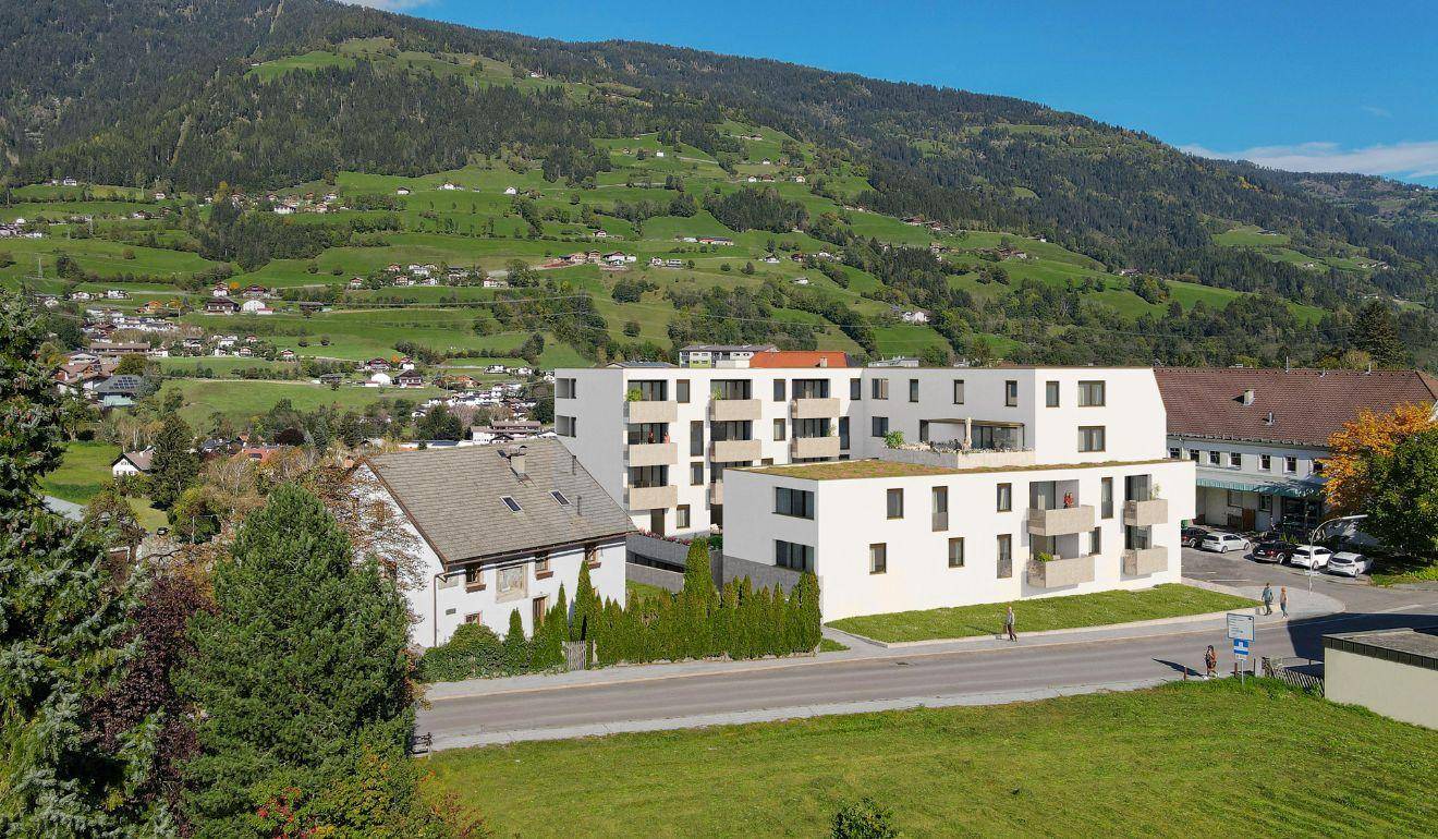 Moderne Wohngebäude in einer grünen Umgebung mit Blick auf die umliegenden Berge und Hügel.