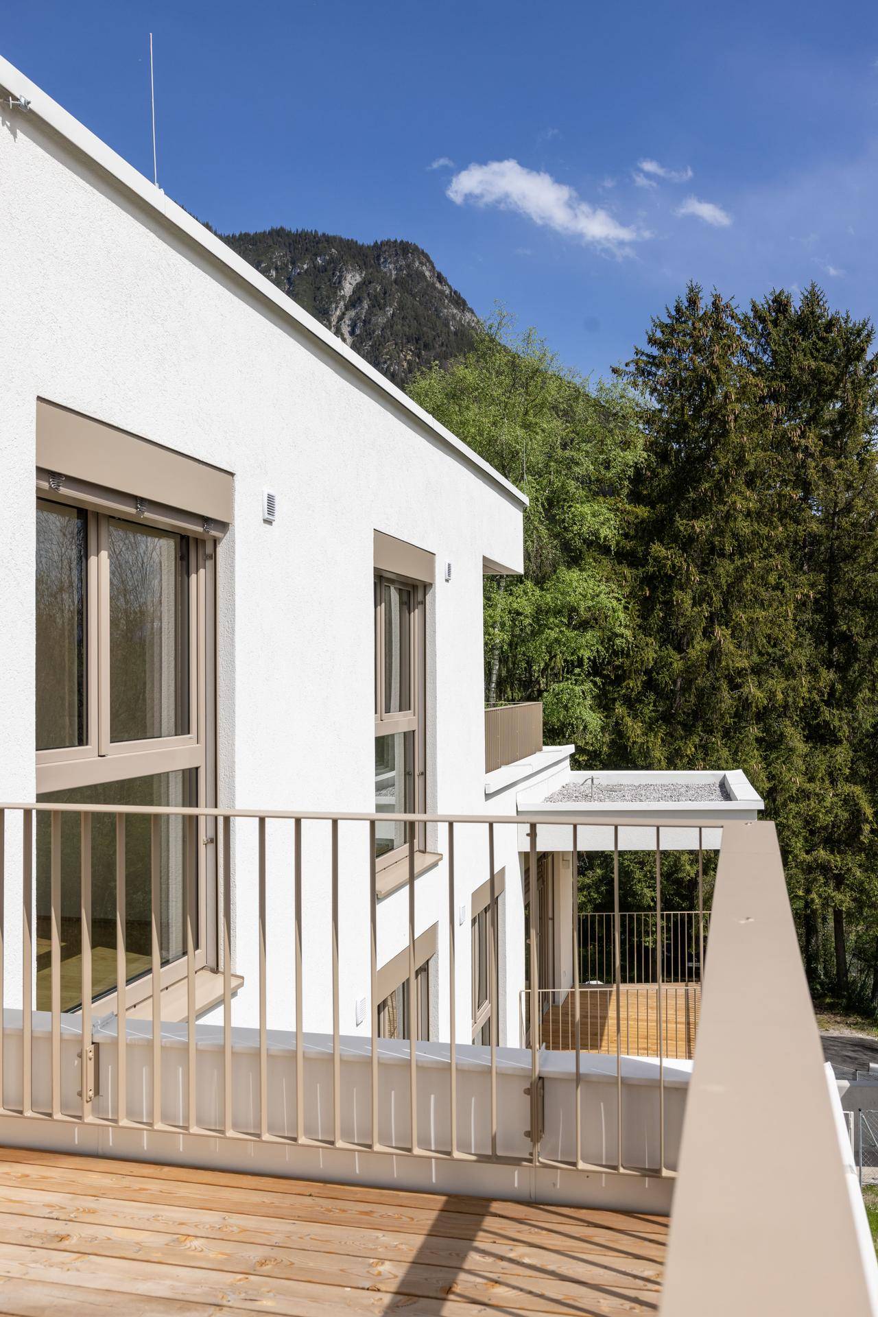 Balkon mit Holzboden und Metallgeländer, bietet einen schönen Blick auf die Berge und Bäume.