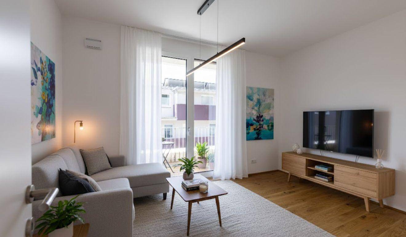Gemütliches Wohnzimmer mit modernem Sofa, Holzboden und Zugang zu einem französischen Balkon.