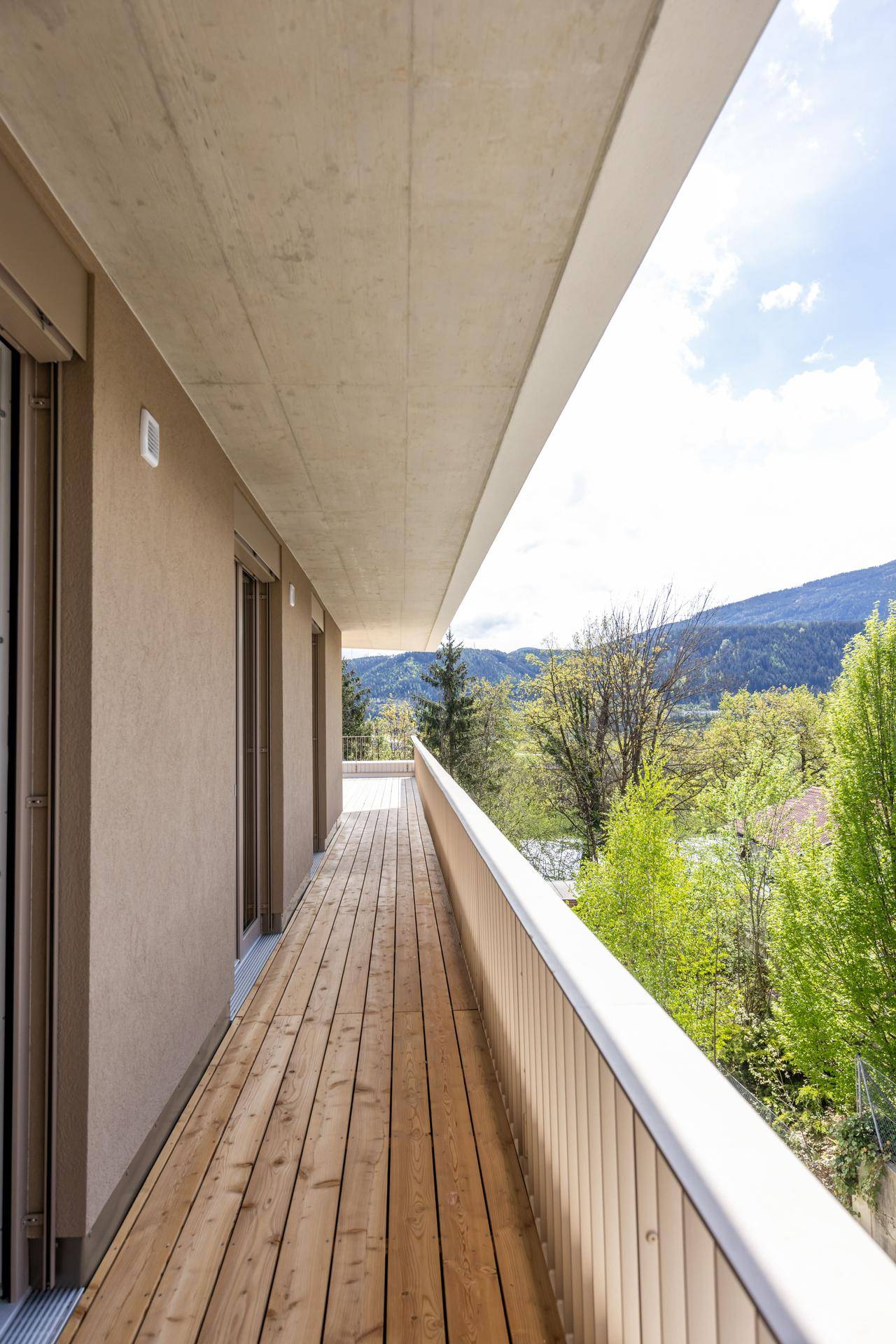 Langer Holzbalkon mit Bergblick und viel Grün, ideal zum Entspannen im Freien.