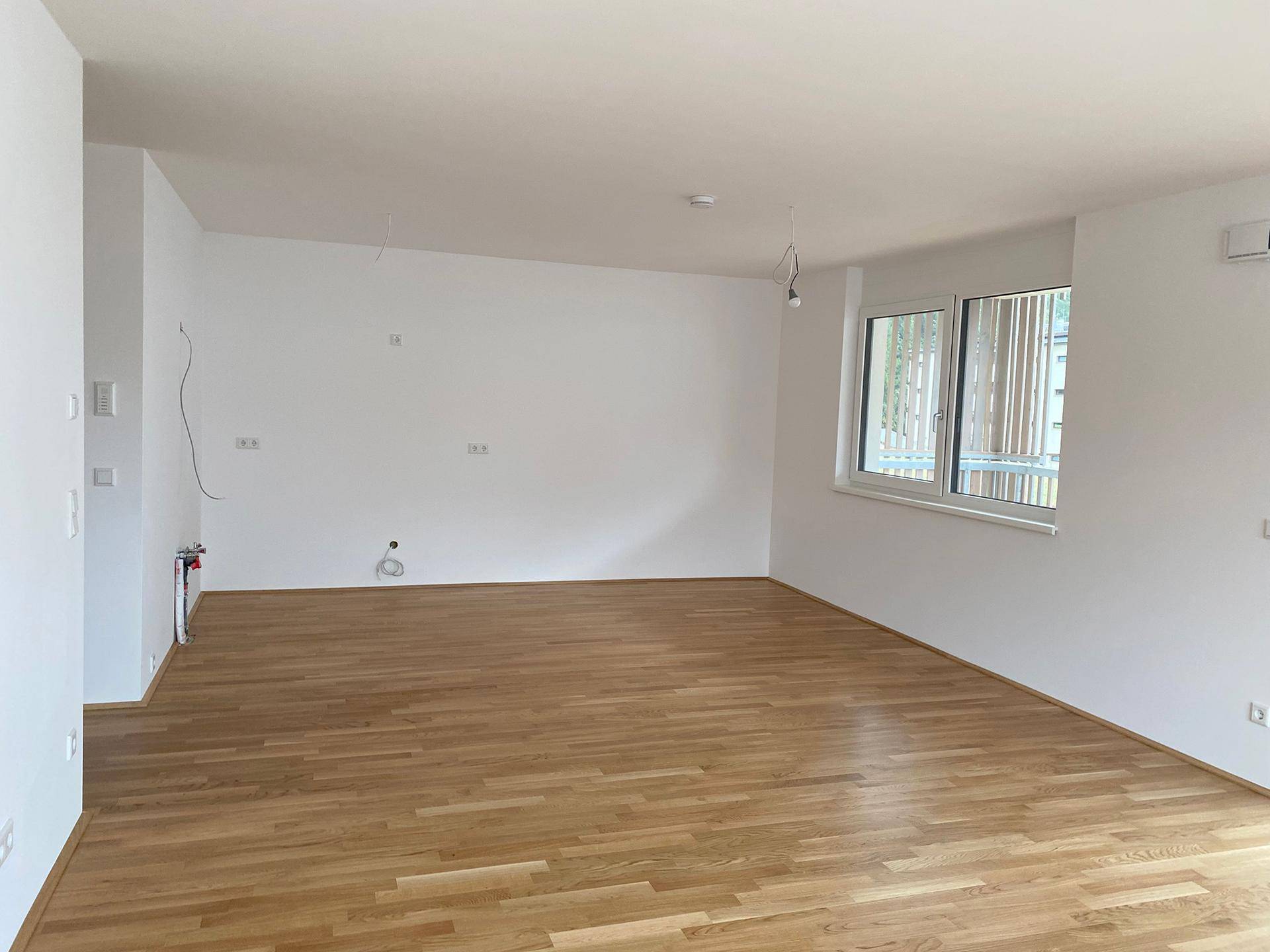 Geräumiger, heller Raum mit Eichenparkett und großen Fenstern, ideal als Wohn- oder Schlafzimmer.