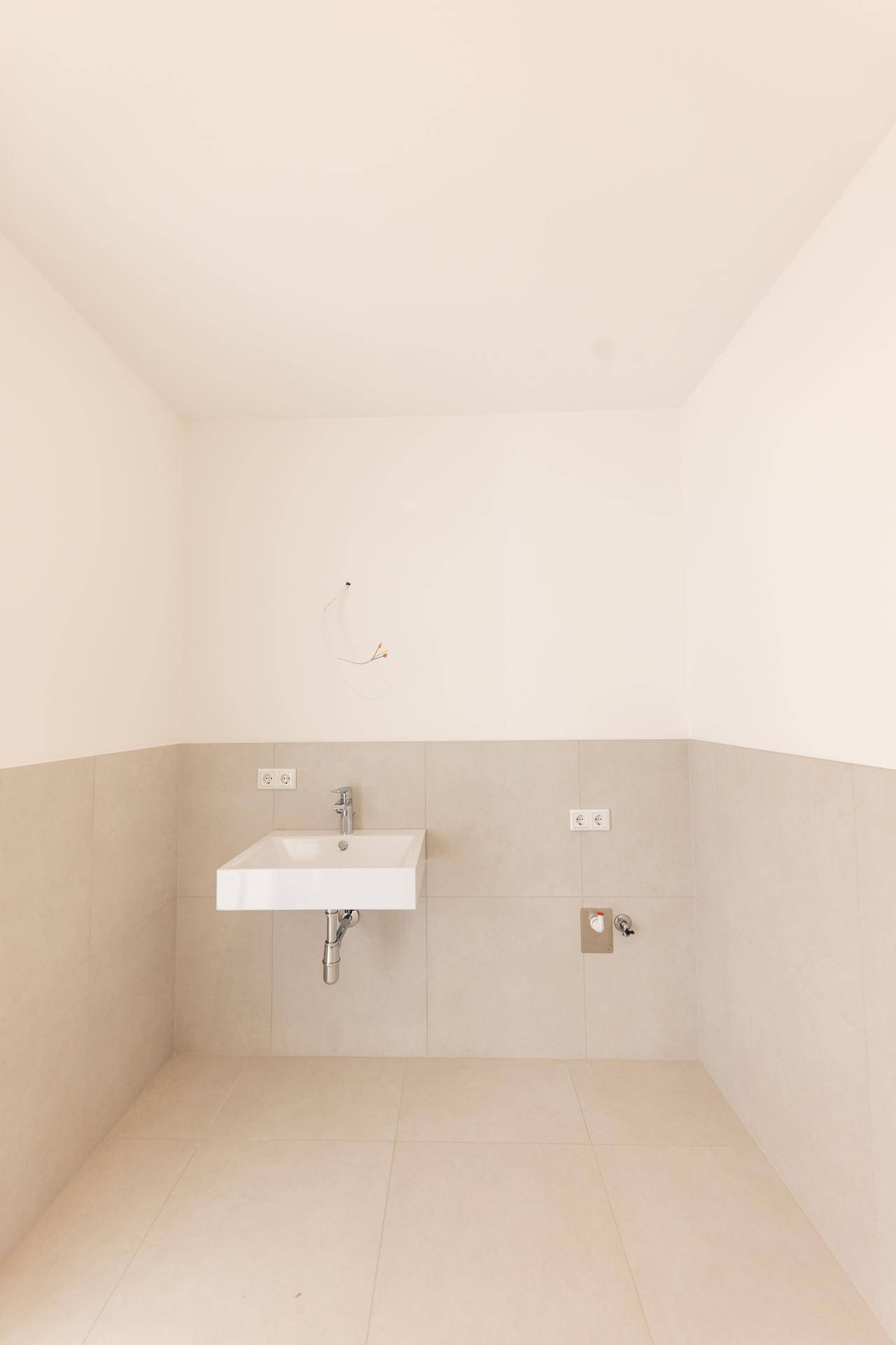 Helles WC mit modernem Waschbecken und hellgrauen Fliesen an Wänden und Boden.