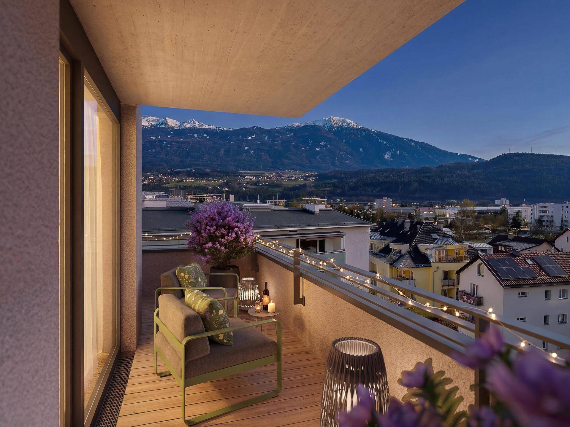 Gemütlicher Balkon mit Lichterkette, Holzboden und Bergblick in der Abenddämmerung.