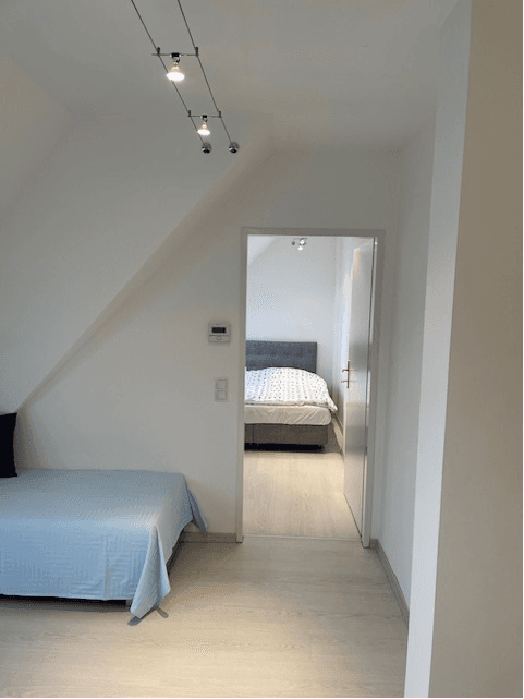 Heller Flur im Dachgeschoss mit Blick in ein Schlafzimmer und hellem Laminatboden.