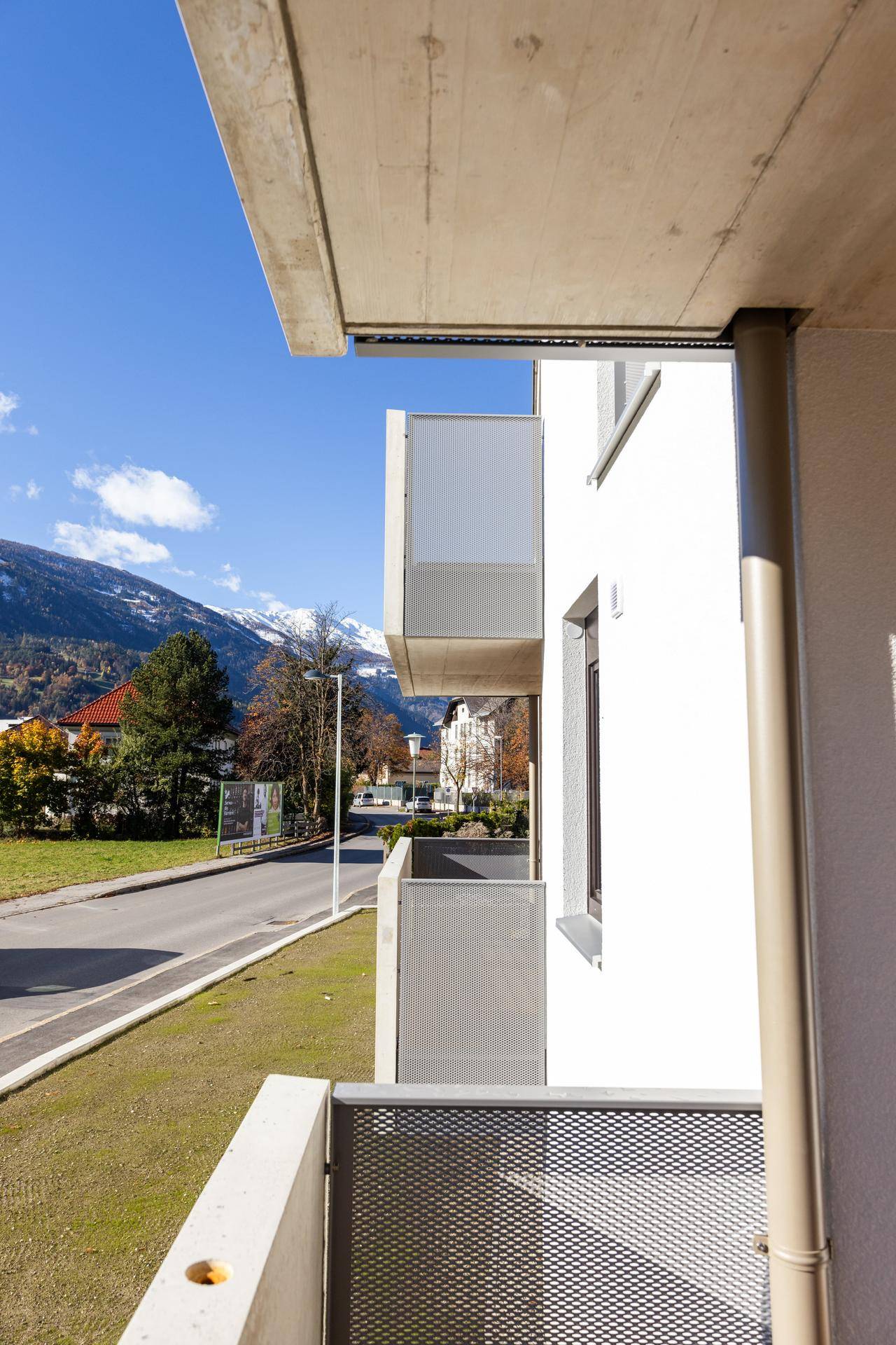 Balkon mit Metallgeländer und Blick auf die Straße sowie die umliegende Berglandschaft.