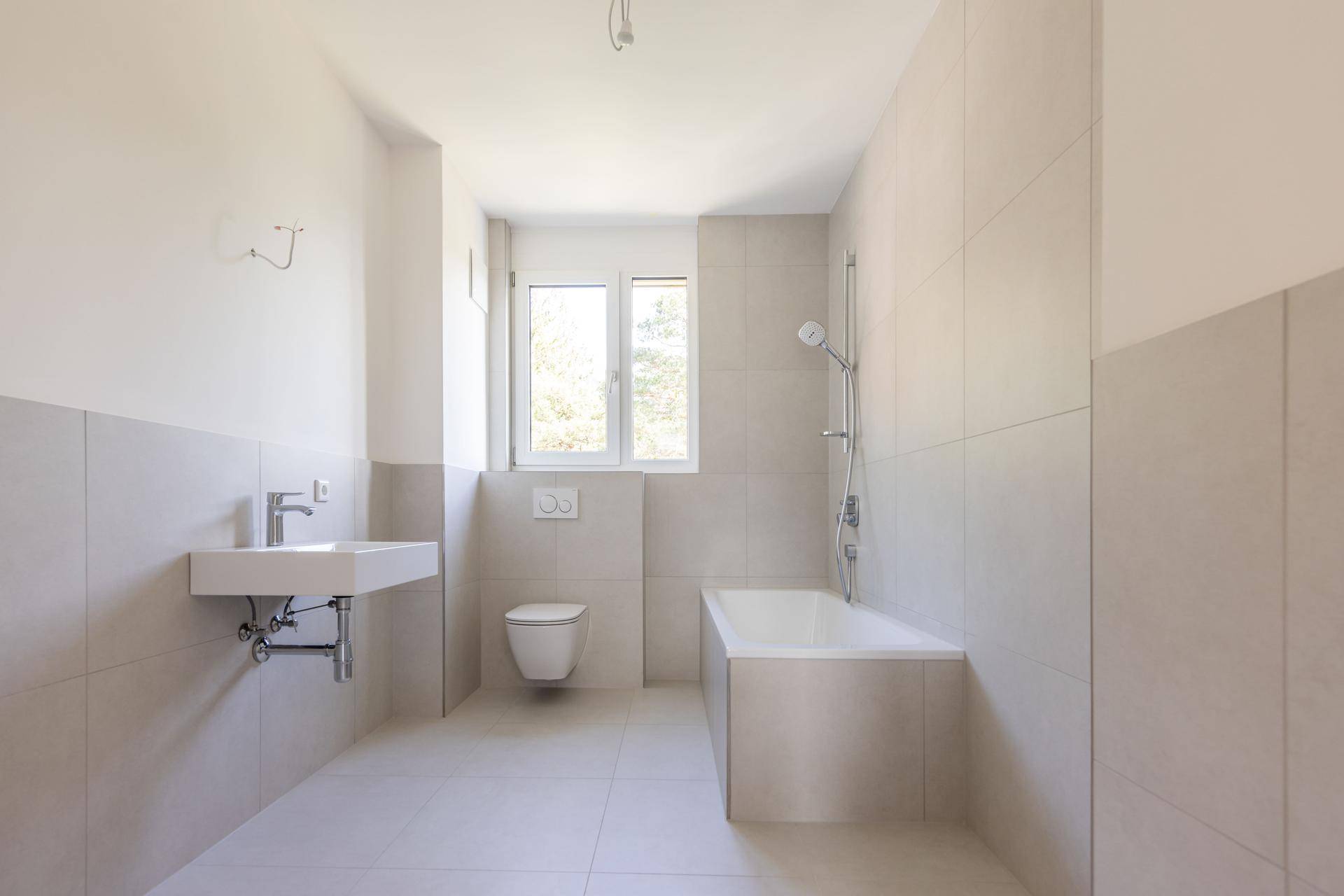 Helles Badezimmer mit Badewanne, wandhängendem WC und modernem Waschbecken.