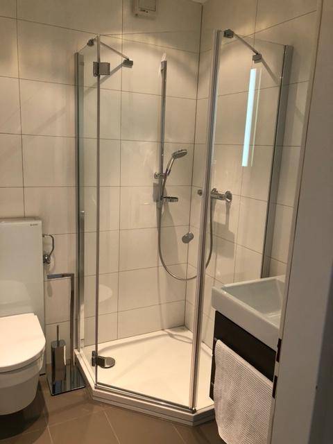 Helles Badezimmer mit Eckdusche, wandhängendem WC und modernem Waschtisch.