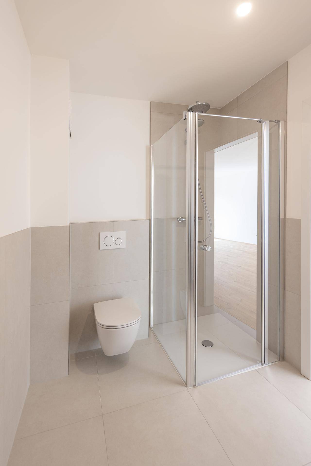 Modernes Badezimmer mit wandhängendem WC und einer Duschkabine aus Glas.
