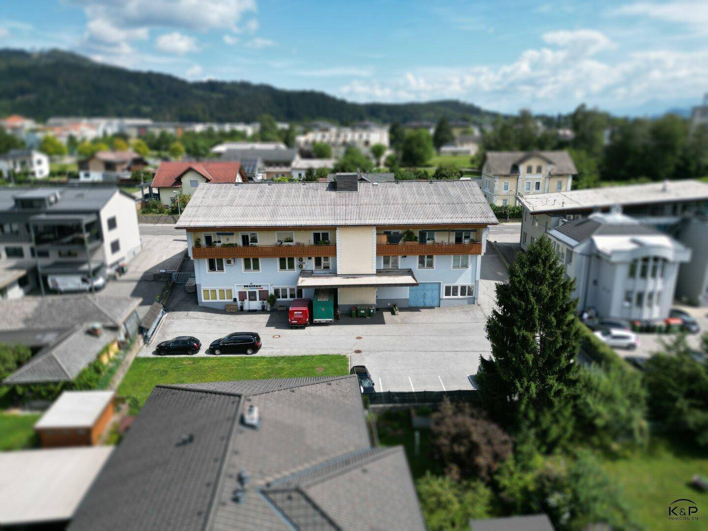 Gesamtansicht des Gebäudes mit seinen Balkonen und dem umliegenden Parkplatzbereich.