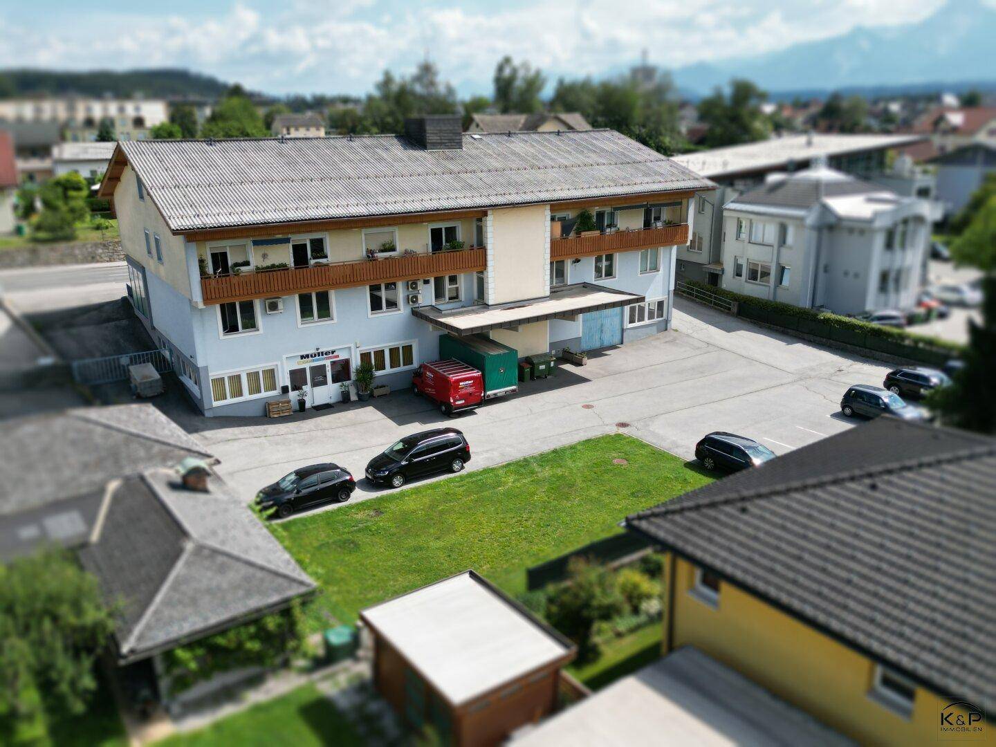 Luftaufnahme des Gebäudes mit Parkplätzen und einer Rasenfläche in der direkten Umgebung.