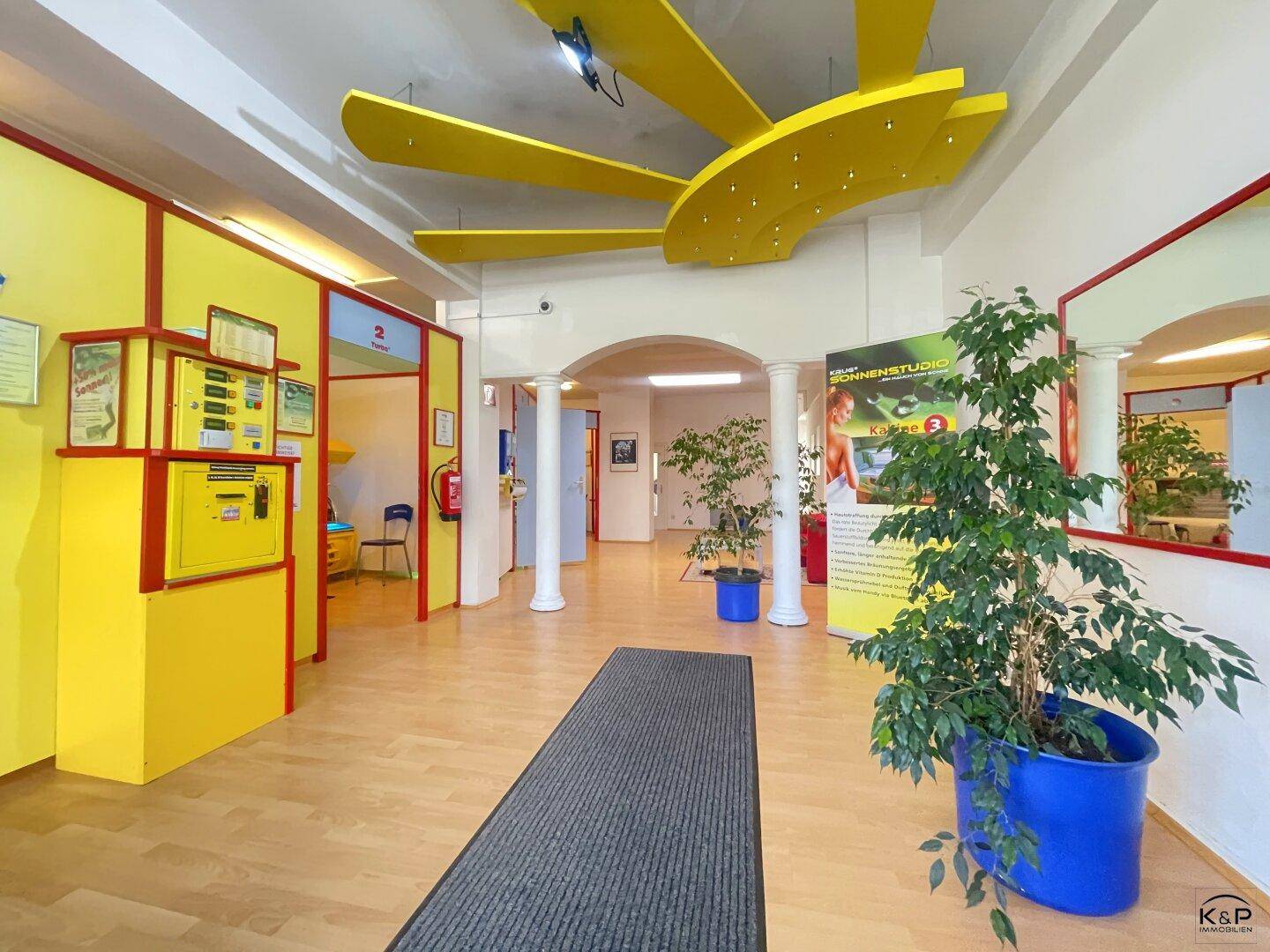 Heller Innenraum mit auffälliger gelber Deckenverkleidung und Pflanzen als Dekoration.