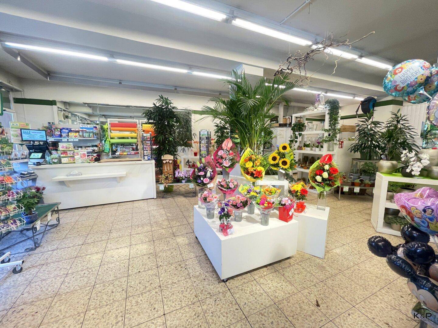 Großer Verkaufsraum mit verschiedenen Blumenarrangements, Geschenkartikeln und Fliesenboden.