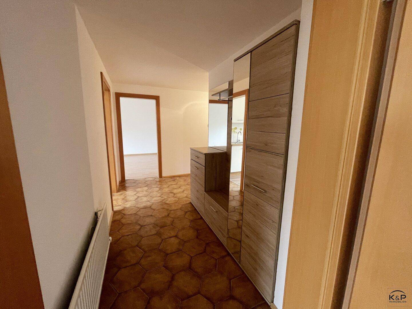 Flur mit gemustertem Fliesenboden und einem modernen Garderobenschrank mit Spiegel.