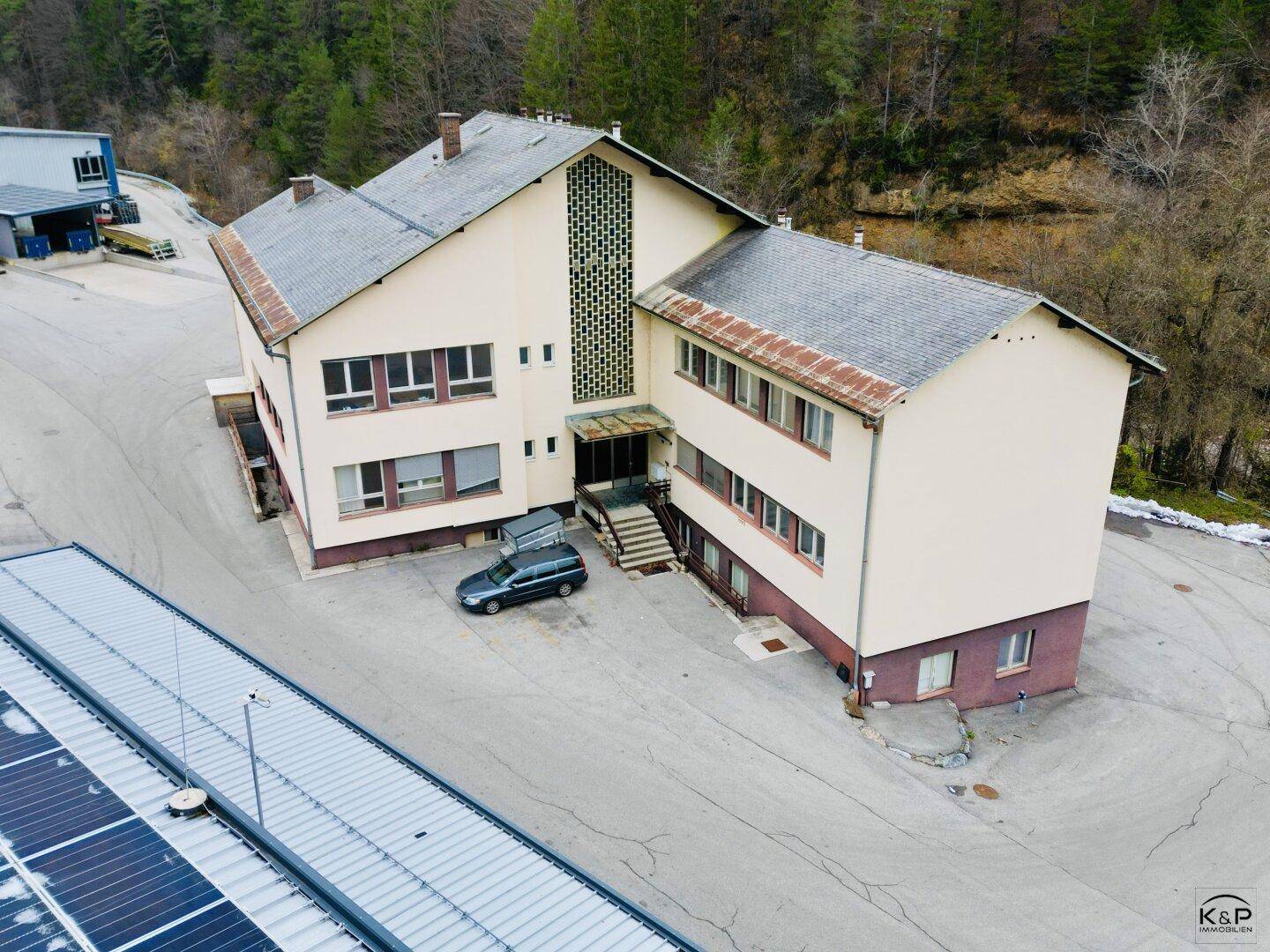 Älteres Geschäftsgebäude mit beiger Fassade, mehreren Etagen und einem Eingangsbereich mit Treppe.