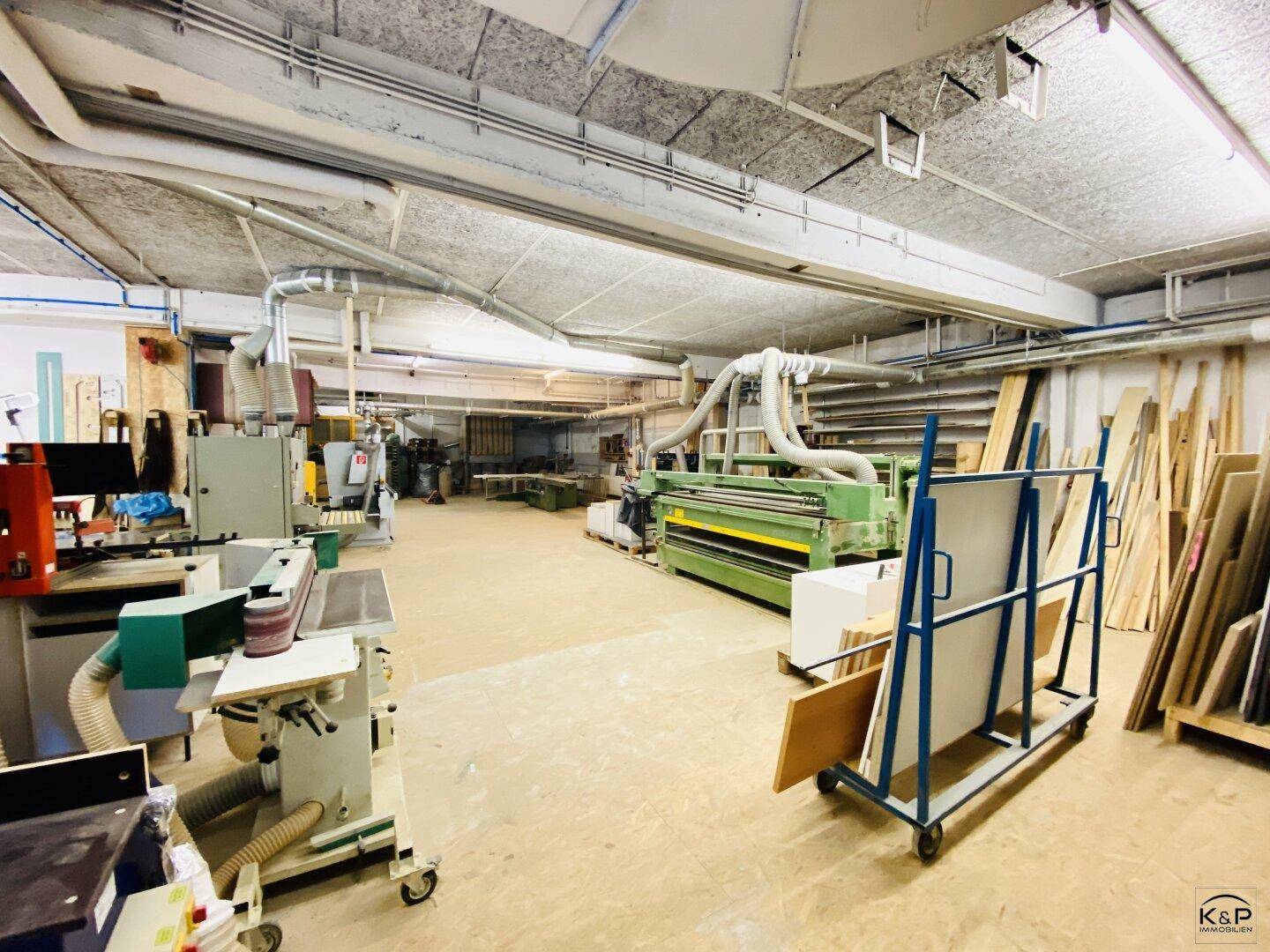 Geräumige Werkstatt mit verschiedenen Holzbearbeitungsmaschinen und Materiallagerung.