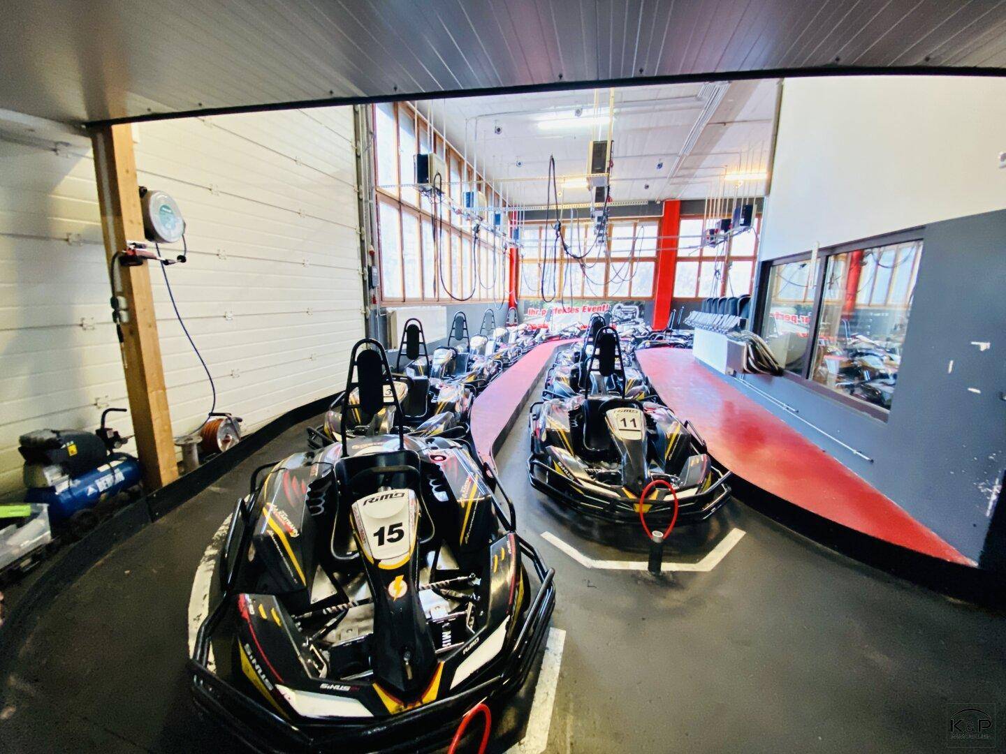 Innenbereich einer Go-Kart-Bahn mit mehreren Karts bereit für das Rennen und breiter Strecke.