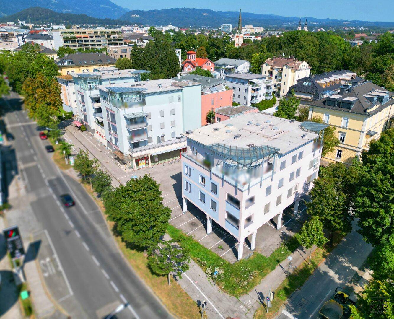 Übersichtliche Luftaufnahme des modernen Gebäudekomplexes mit umliegender Bebauung und grünen Bäumen.